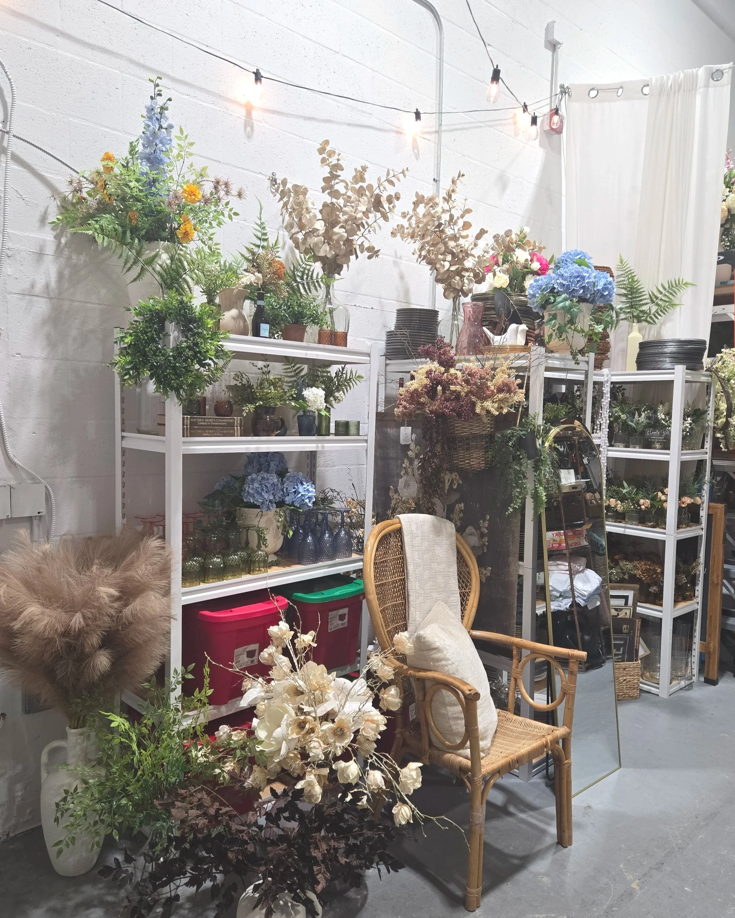 Decor, faux flowers, wicker chair in storage room at Oasis Events Collective in Sarasota FL.  