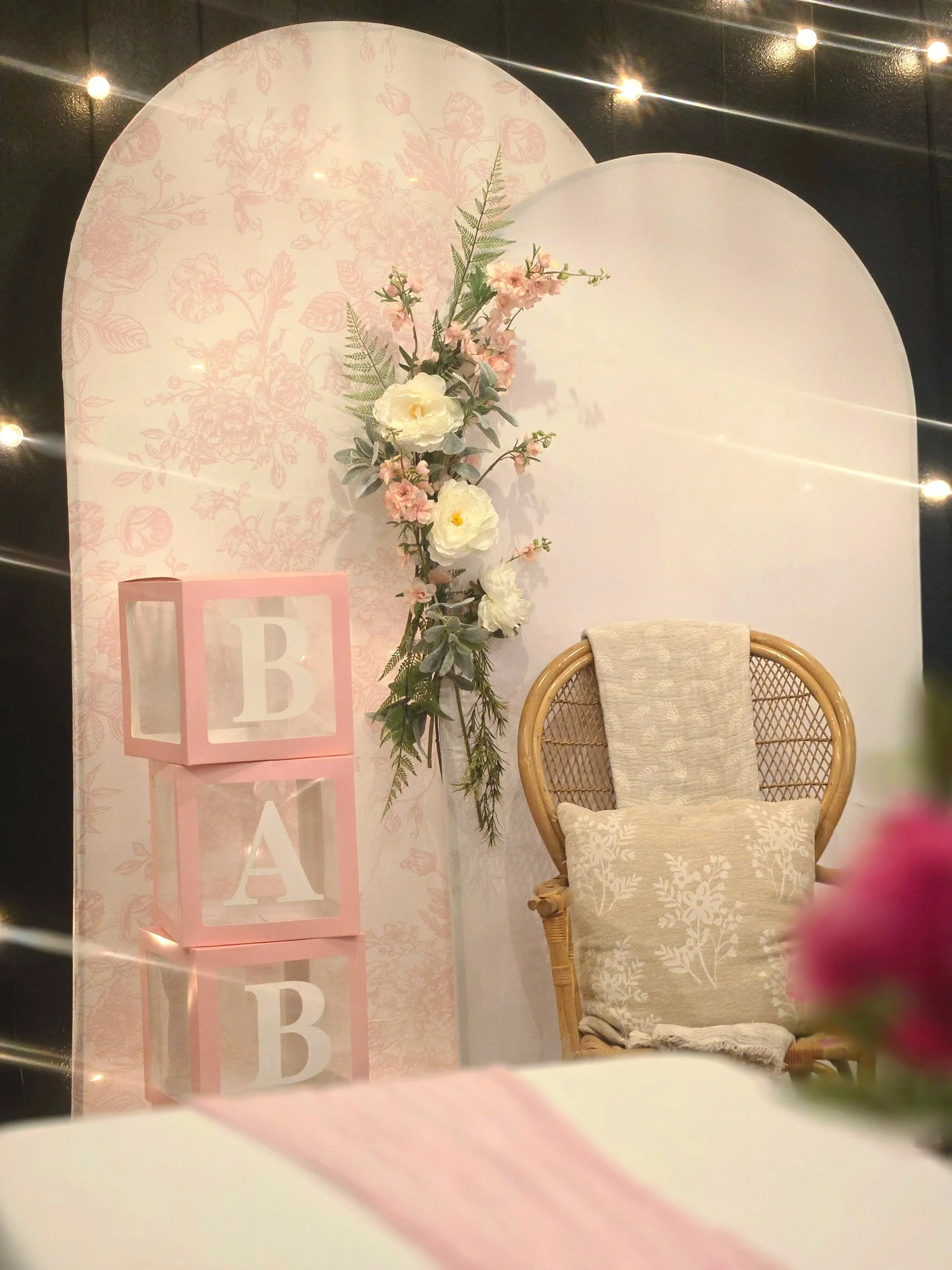 Double arches and wicker chair with floral display for a baby shower at Oasis Events Collective in Sarasota Florida