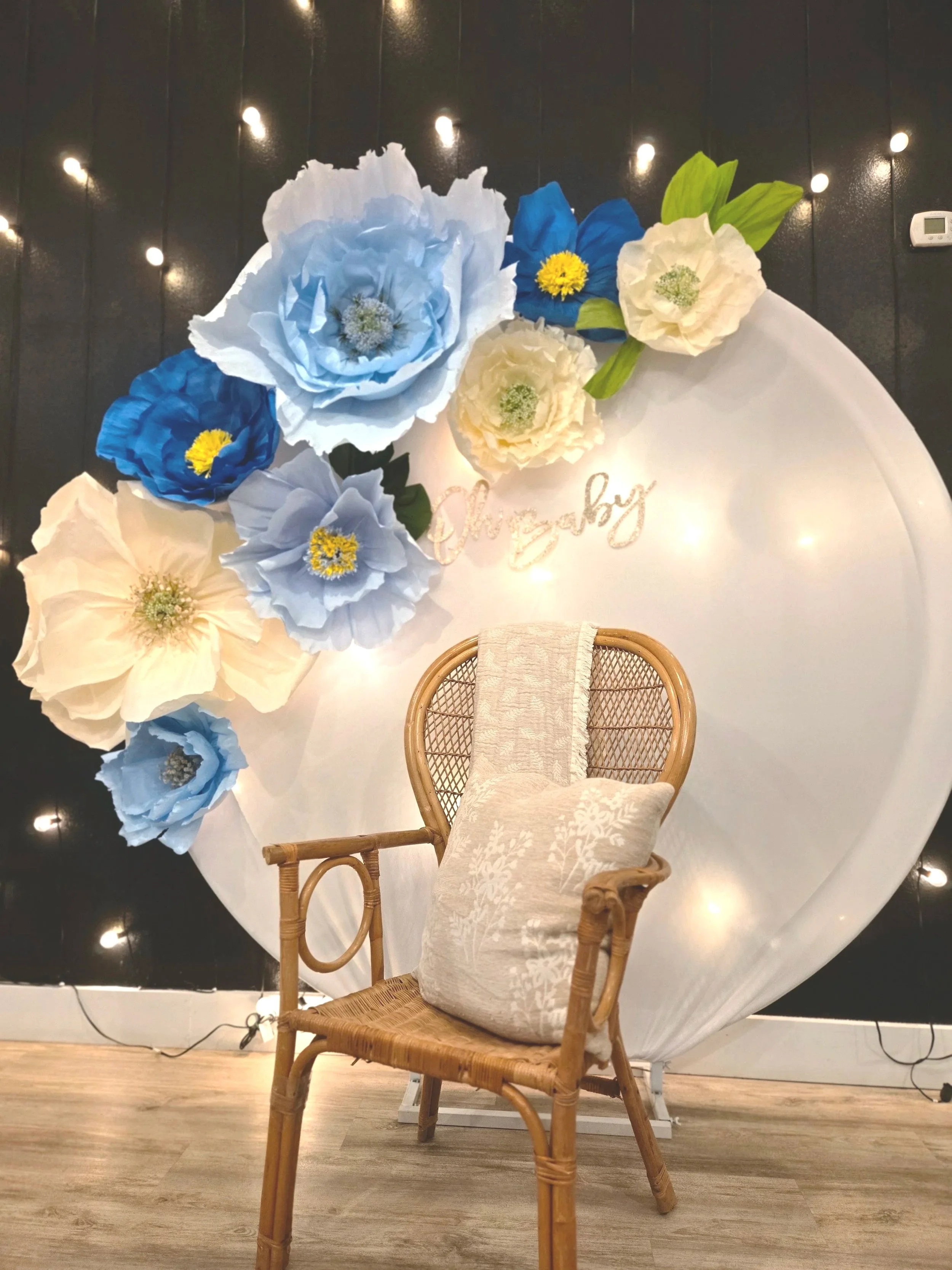 A lovely arch backdrop with large florals, wicker chair and black lighted wall for a baby shower in Oasis Events Venue in Sarasota, FL
