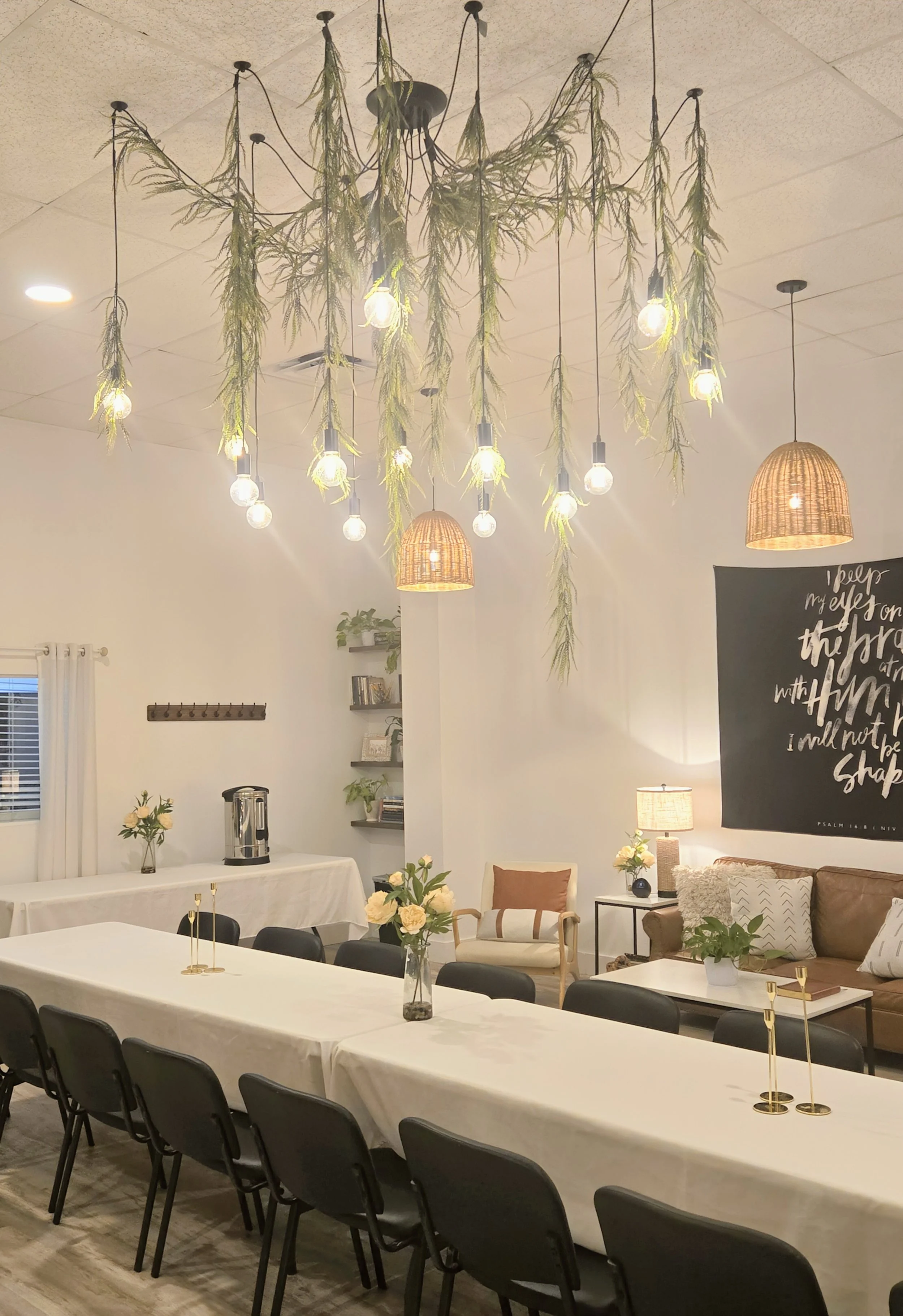 Indoor space decorated with string lights, hanging plants, bookshelves, and cozy seating area, set up for a gathering or event.  Cozy, intimate venue in Sarasota FL. Great space for baby showers, bridal showers, grad parties, birthday parties.  