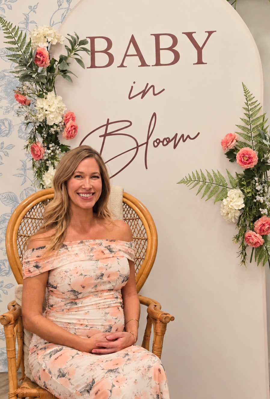 Baby shower at Oasis Events in Sarasota FL.  Mom-to-be on wicker chair in front of arch with flowers.