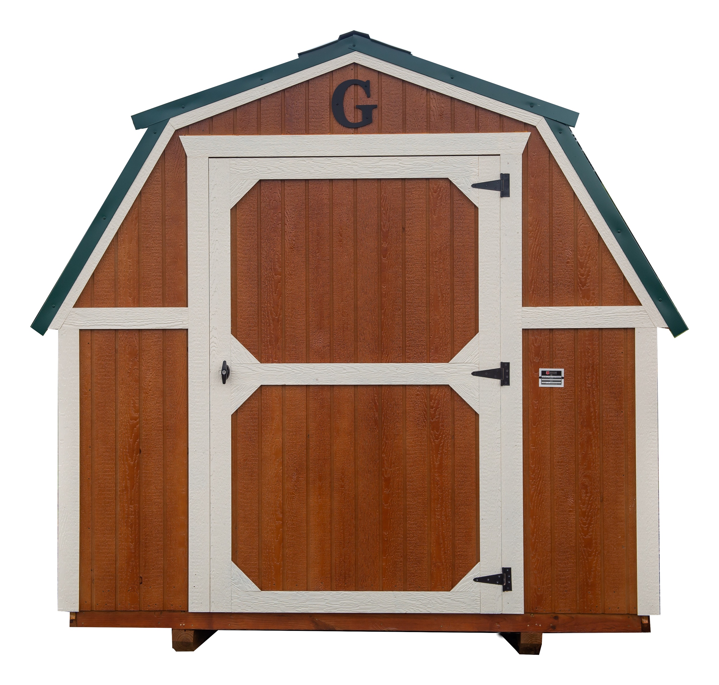 Small wooden shed with brown walls and white trim, featuring a gable roof and a double door. A letter 'G' is mounted above the door.
