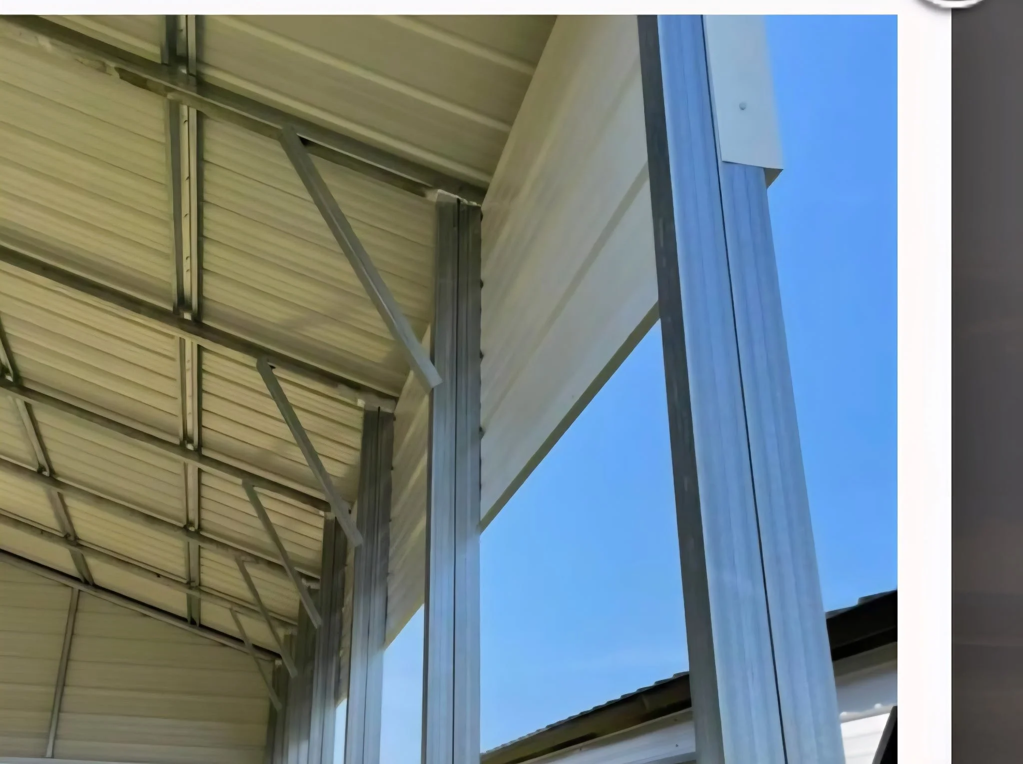 Metal framework supporting a roof made of corrugated metal sheets, against a clear blue sky.