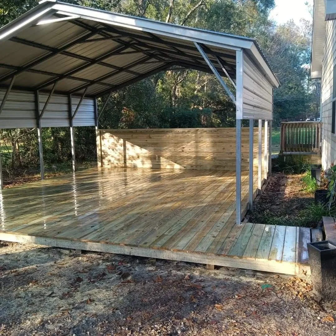 Newly built wooden deck with a metal and metal-paneled roof structure in a backyard, next to a house with a small wooden railing.