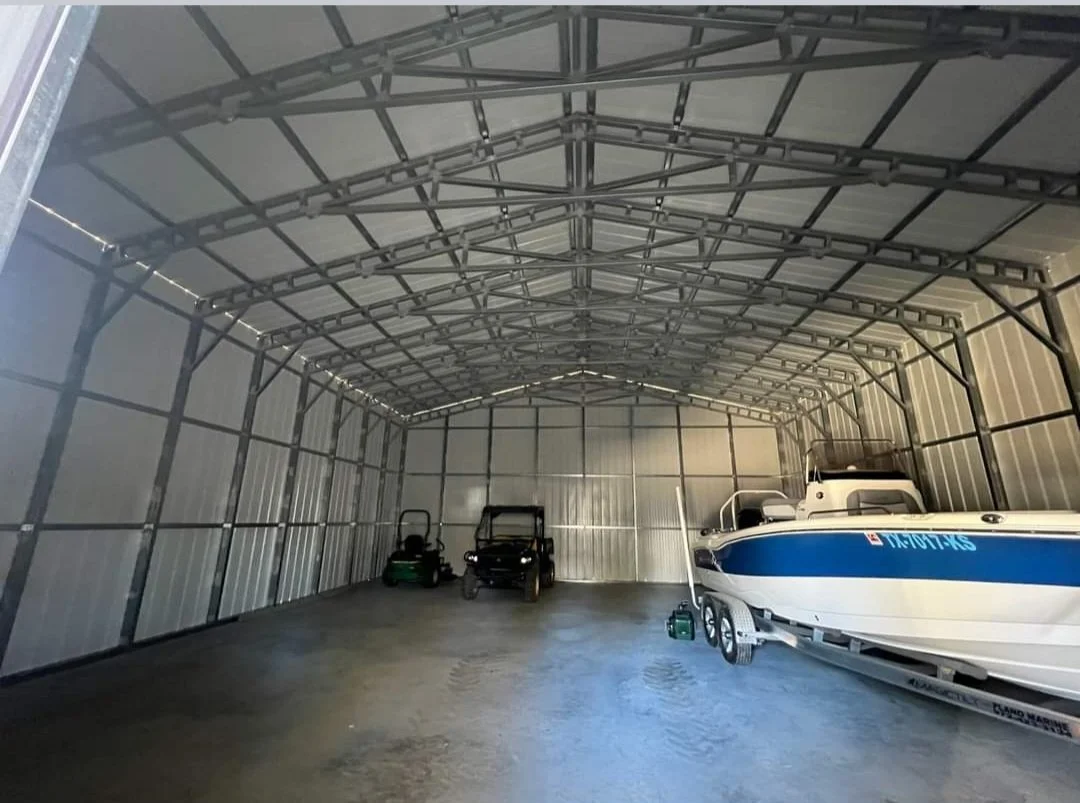 Large metal boat storage shed with a white and blue boat, two golf carts, and some small equipment inside.