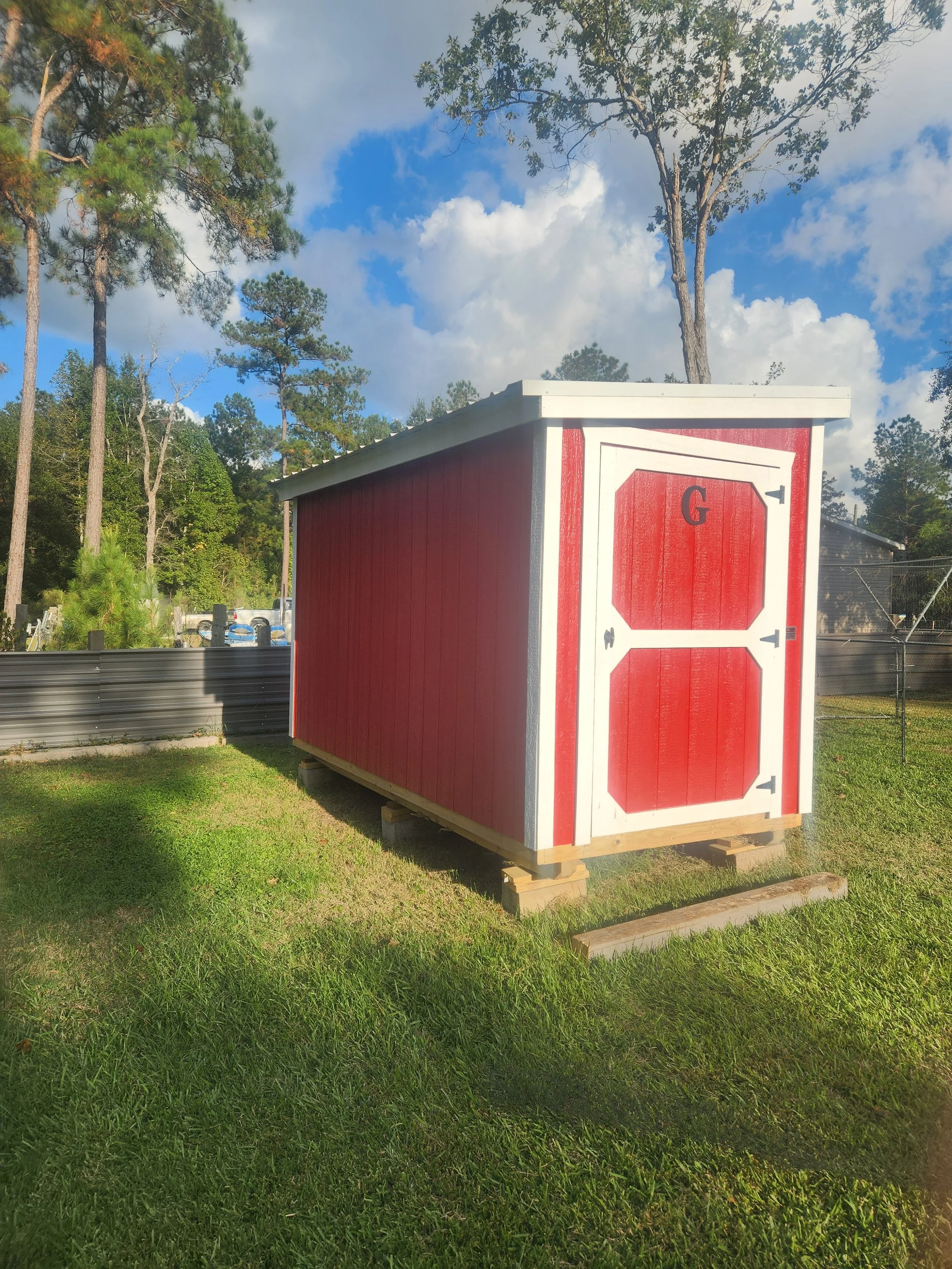 A small red and white shed with a door featuring an 