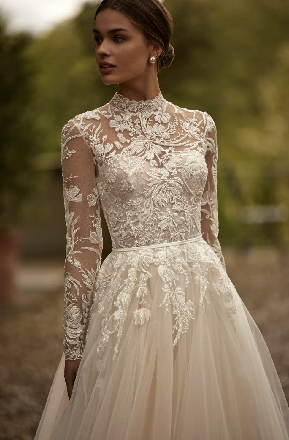 Bride in a floral lace wedding dress with long sleeves and high neck.