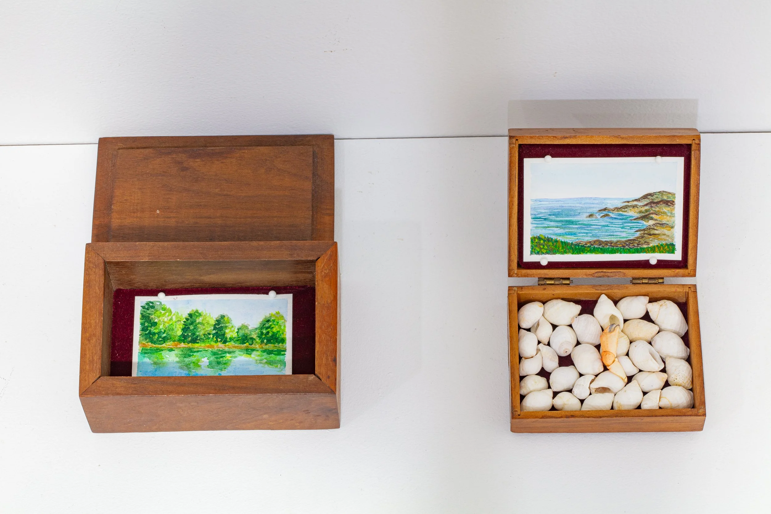 (left to right) i carry it with me: Chattahoochee River, 2025, wooden box, velvet, watercolor on paper. i carry it with me: Atlantic Ocean, York, ME, 2025, wooden box, velvet, periwinkle shells, crab leg.  photo credit: Sindayiganza Photography