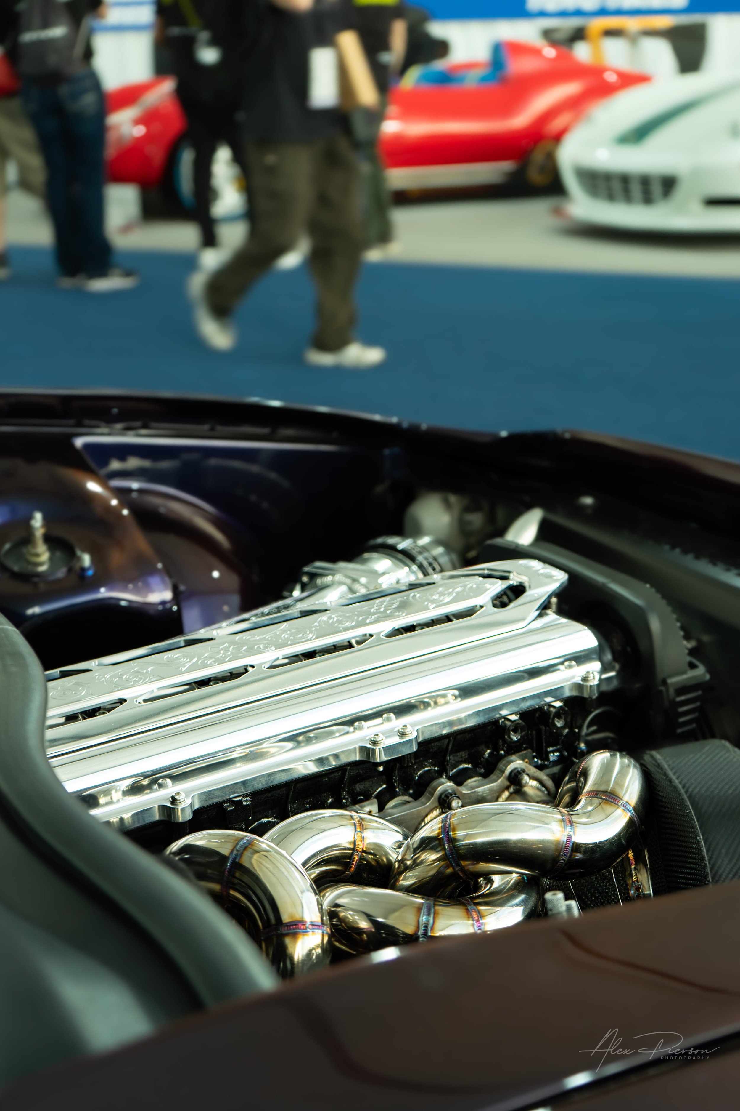 Close up of a highly polished intake manifold and custom exhaust headers on a Toyota Chaser engine at SEMA.
Under the hood perfection. A close-up look at the mirror-polished intake manifold and beautifully welded exhaust headers on this custom JDM en