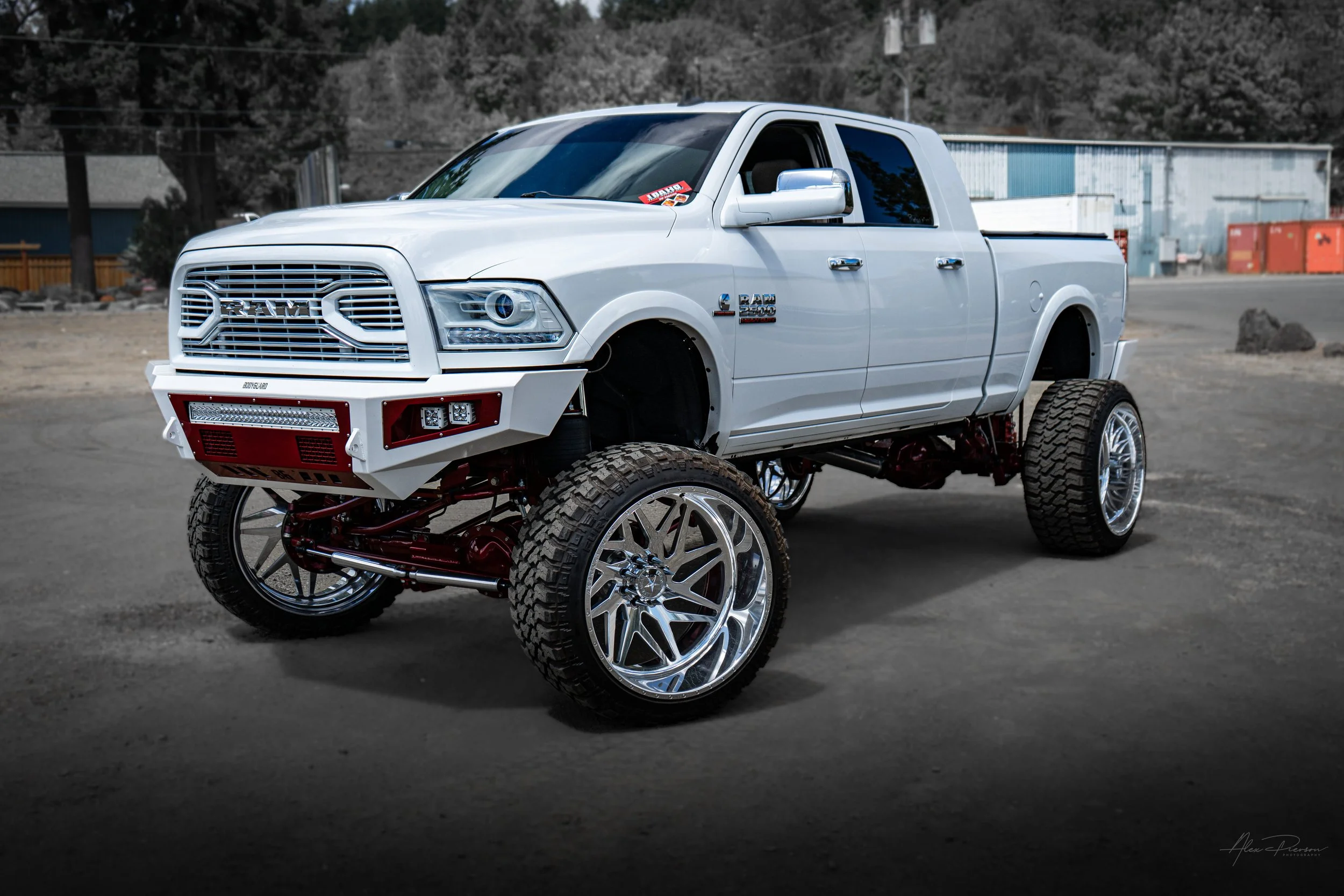Stunning front 3/4 view of a custom white Ram 2500 featuring a massive red Kelderman air suspension lift, Bodyguard front bumper, and polished American Force wheels.
 White lifted Ram 2500, American Force wheels truck, Kelderman lift stance, custom s