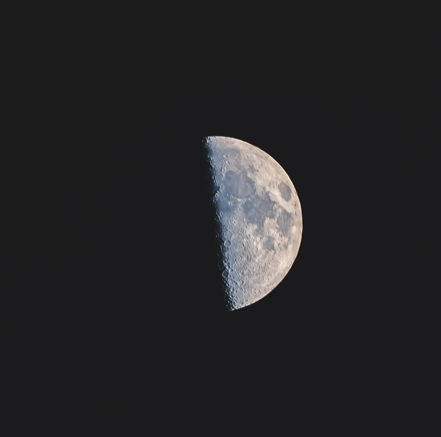 High-resolution astrophotography showing the craters and details of a glowing half moon against a pitch-black night sky.