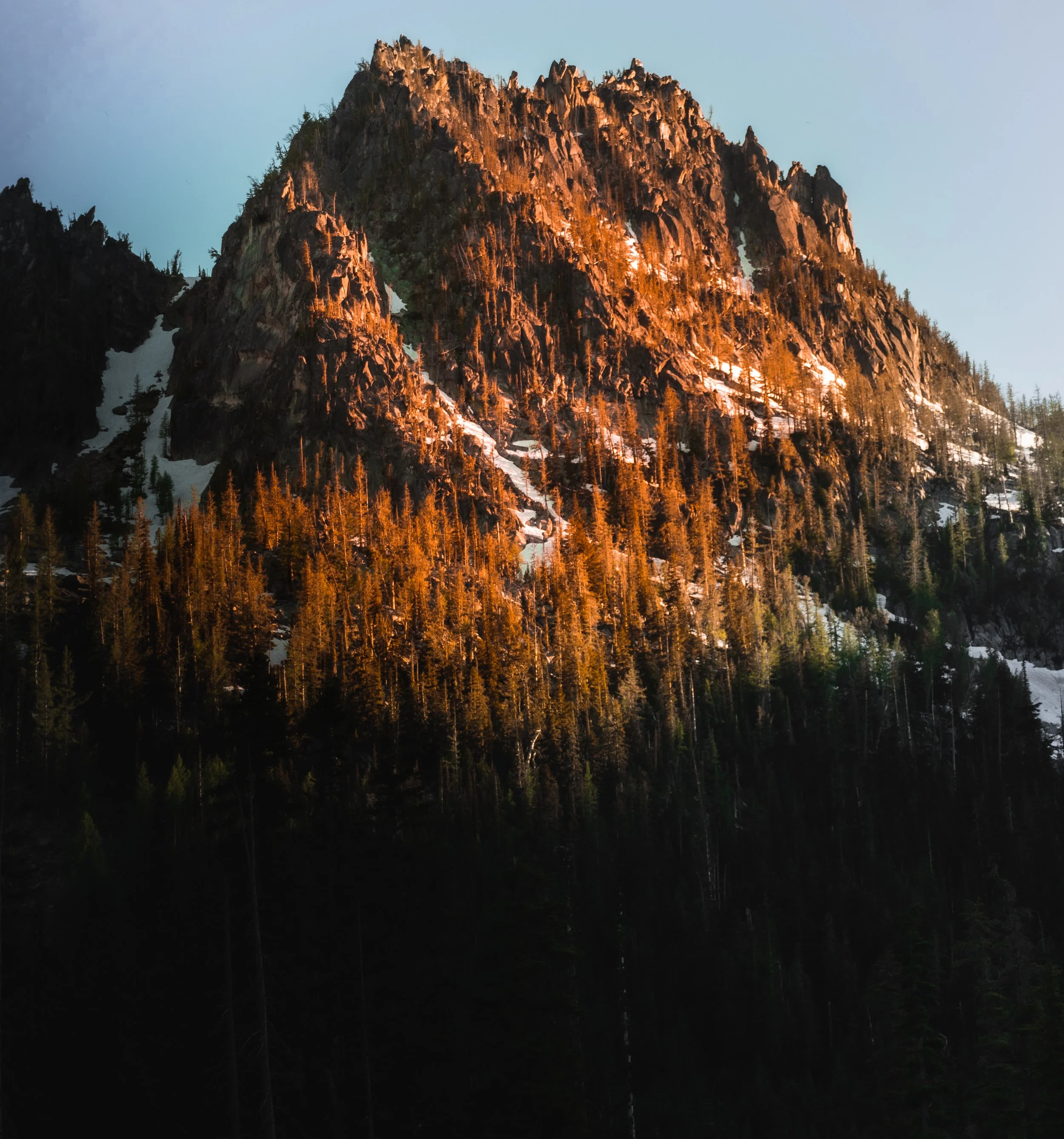 Dramatic golden hour light illuminating a rugged mountain peak and alpine trees in the Pacific Northwest – fine art landscape photography.