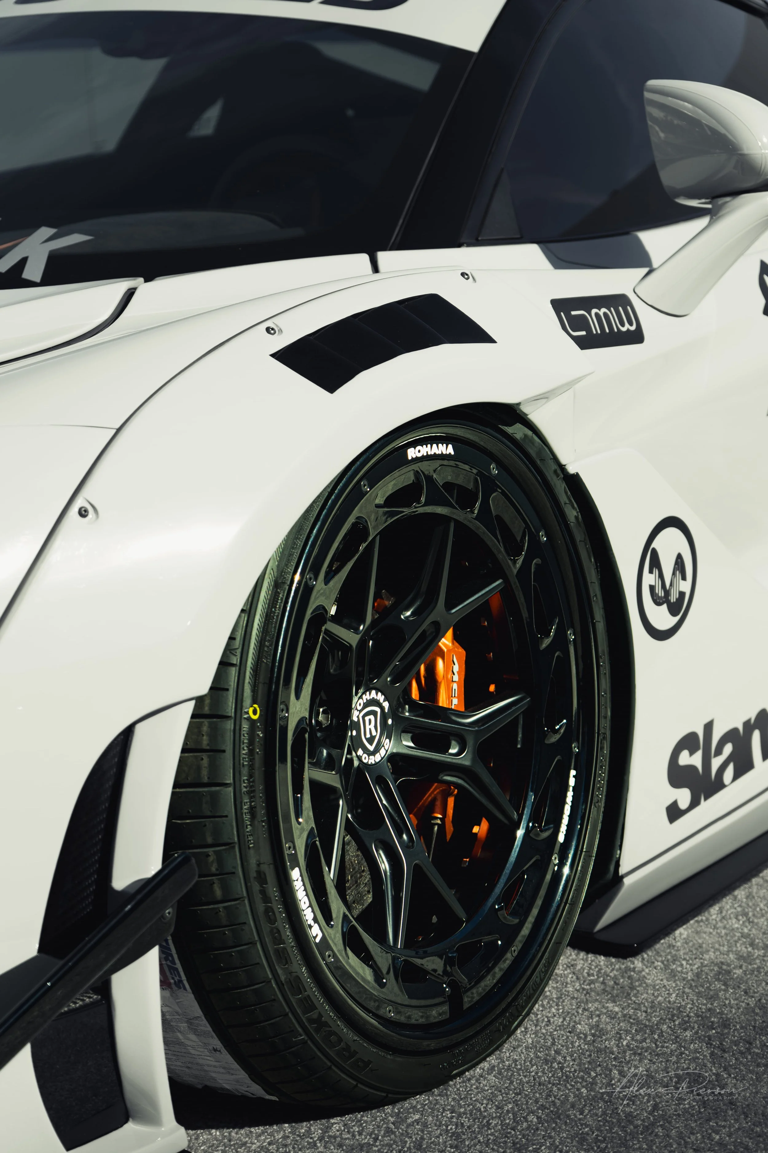Close up of a black Rohana forged wheel and orange McLaren brake caliper inside a widebody fender.
 Tucking perfectly into the custom Liberty Walk fenders, these gloss black Rohana forged wheels frame the massive, bright orange McLaren brake calipers