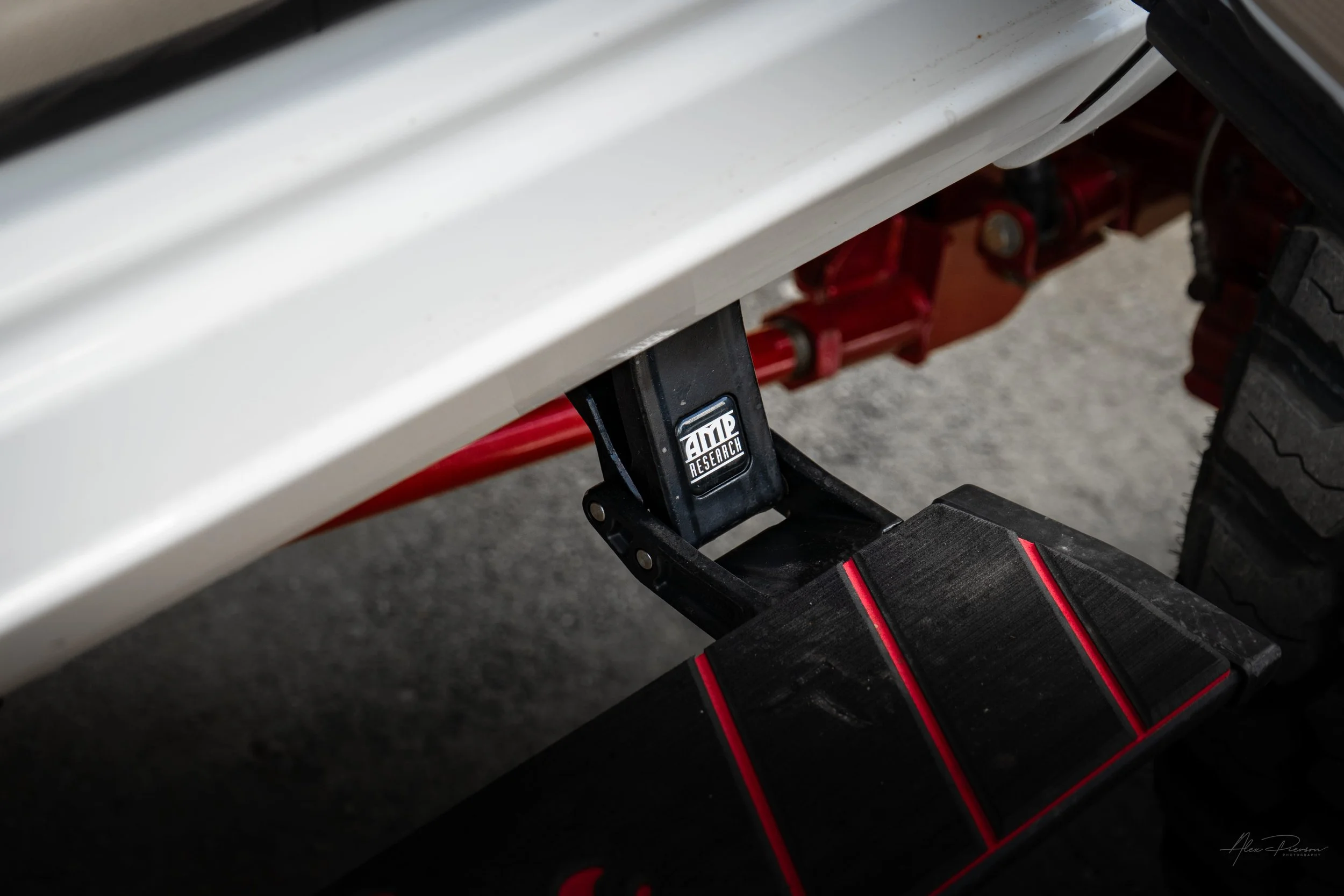 Deployed AMP Research automatic power step running board on a custom lifted Ram 2500 featuring red powder-coated undercarriage suspension.
AMP Research steps, power running boards, truck drop steps, Ram 2500 side steps
AMP Research automatic deployin
