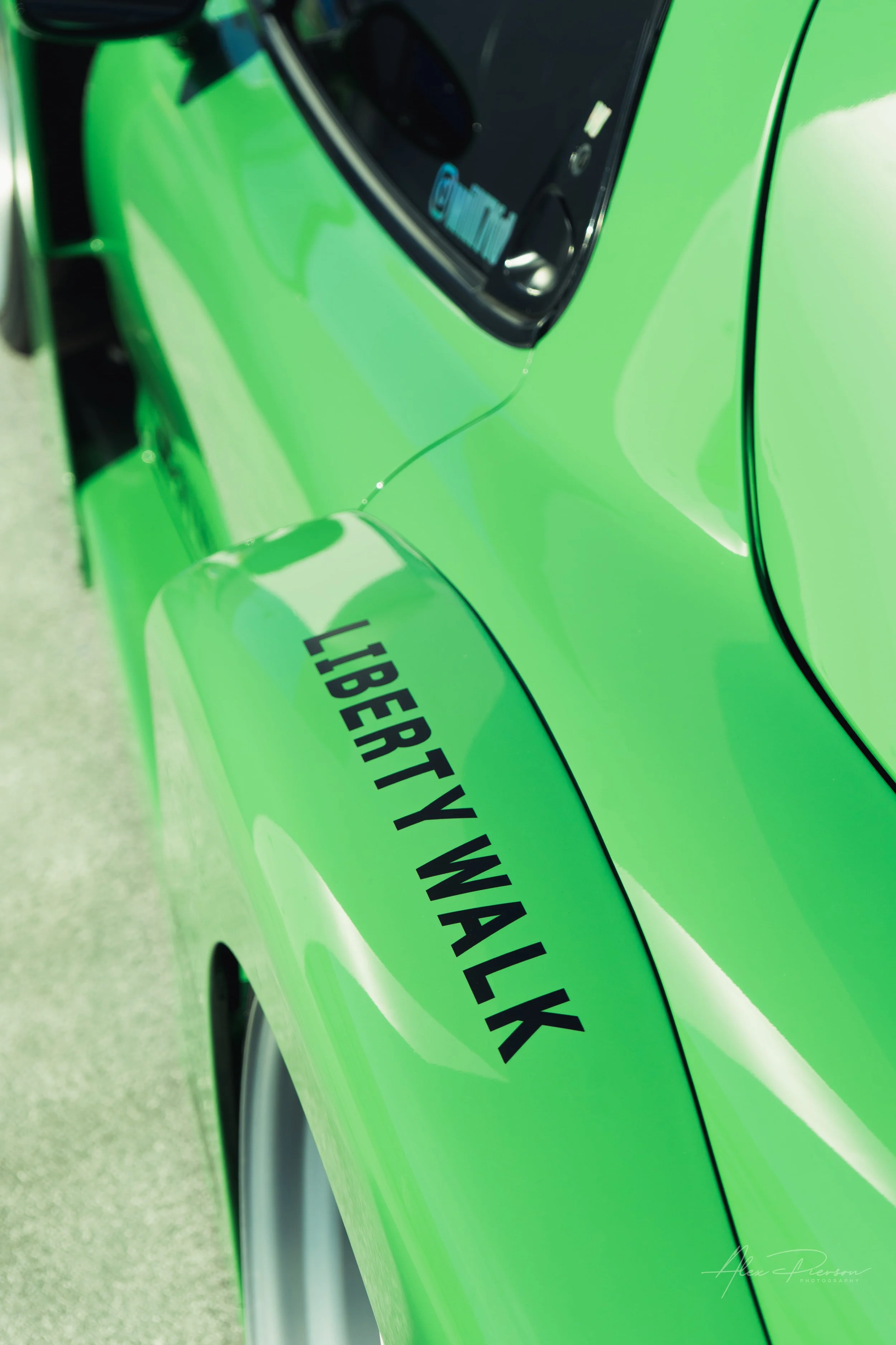 Close up of a smooth green widebody fender with a black Liberty Walk decal on a custom Mazda at SEMA.
Iconic JDM styling. The unmistakable sculpted curves and bold branding of a Liberty Walk widebody kit on a vibrant green Mazda RX-7 build in Las Veg
