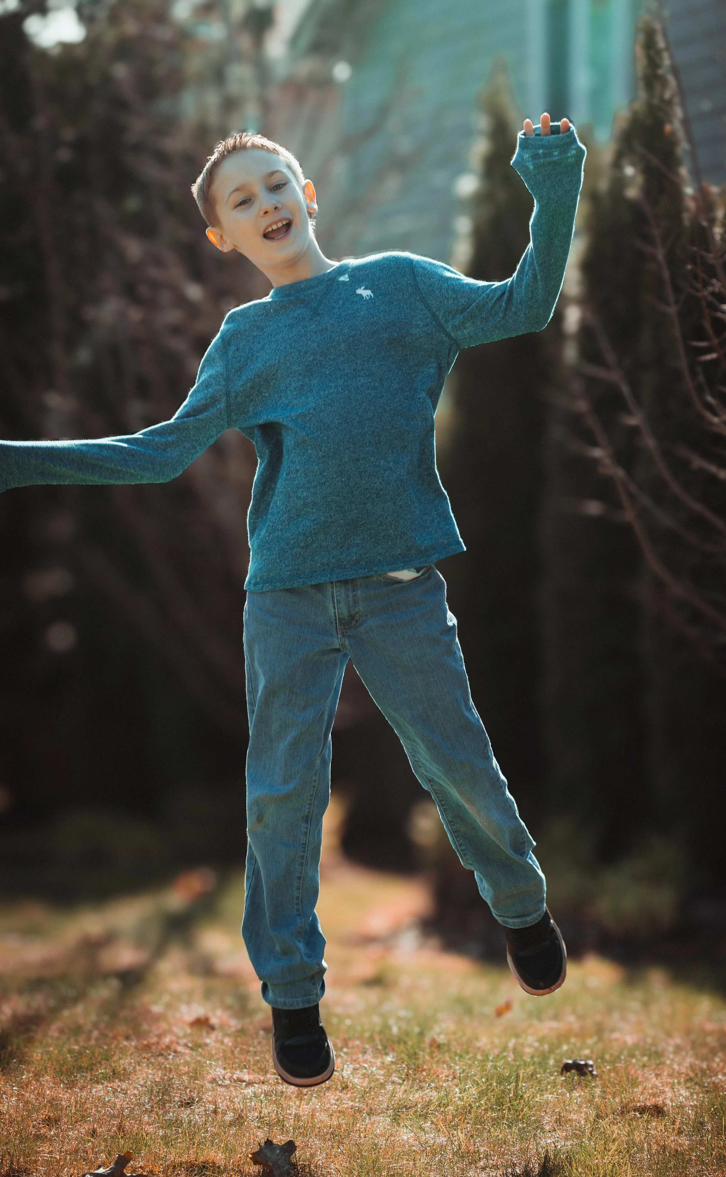 boy in a blue shirt jumping in the air during a family photoshoot in Tumwater, WA – Pacific Northwest lifestyle family and children's photography.