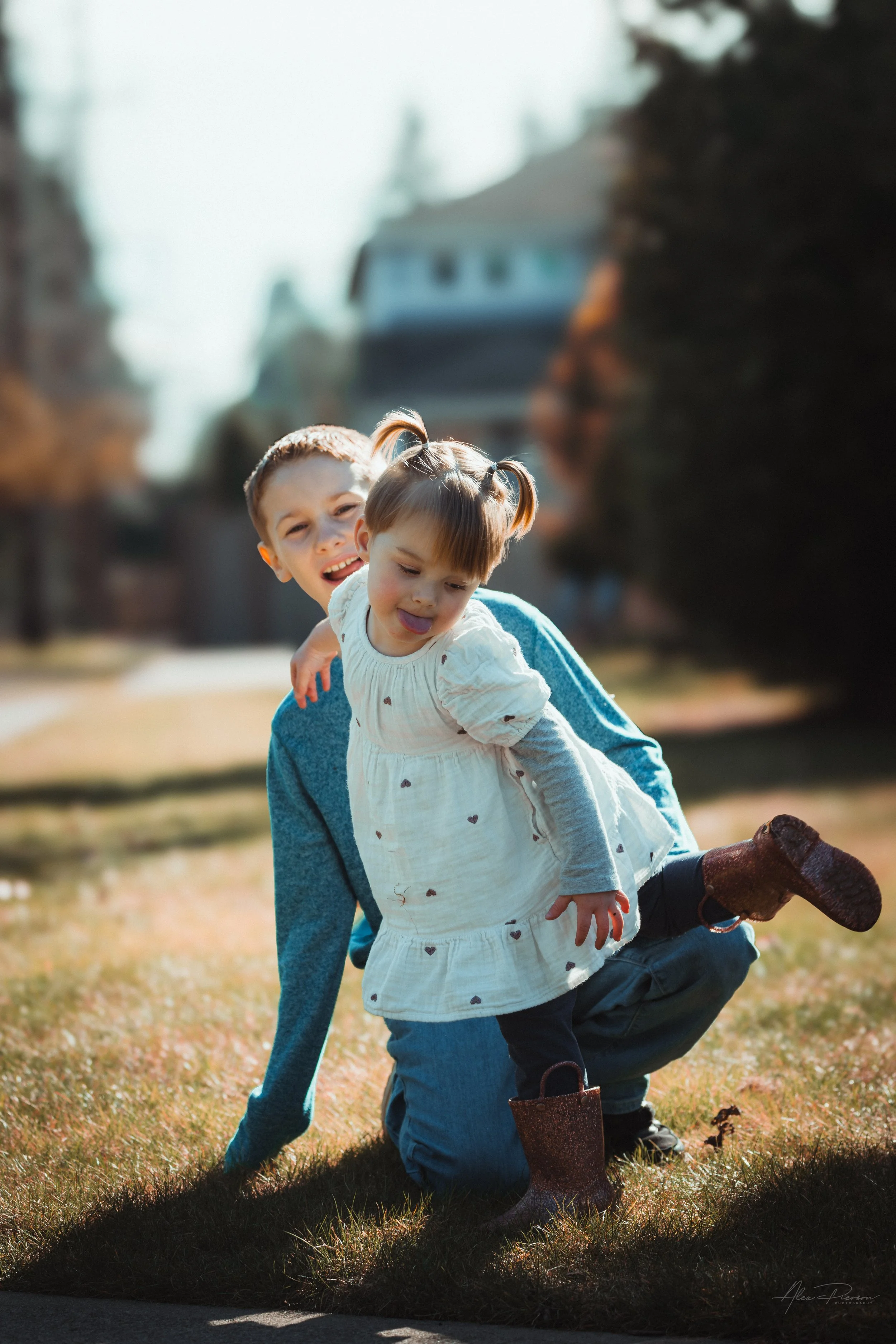 Little girl playfully making silly faces while balancing on one foot with her cousin during a candid family photo session Tumwater, WA – Pacific Northwest lifestyle family and children's photography.