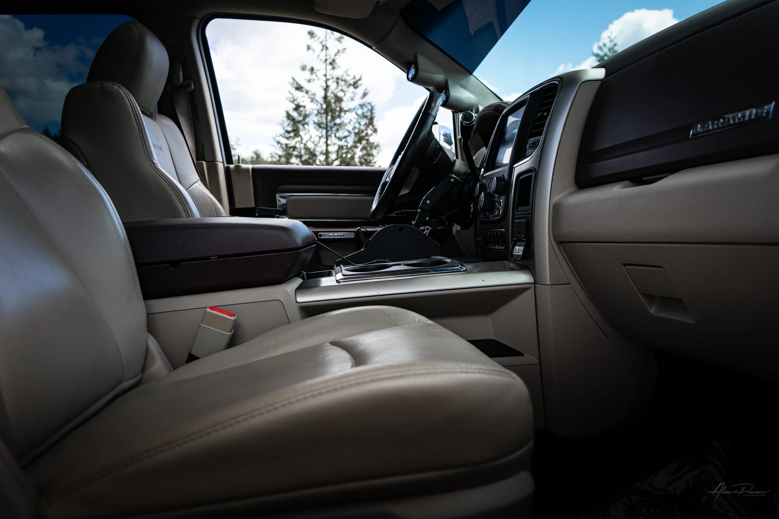Interior cabin view of a custom Dodge Ram 2500 Laramie edition, featuring premium tan and brown leather seating, a spacious center console, and A-pillar gauges.

Ram 2500 seats, tan leather truck interior, Laramie cabin, diesel pillar gauges.
premium