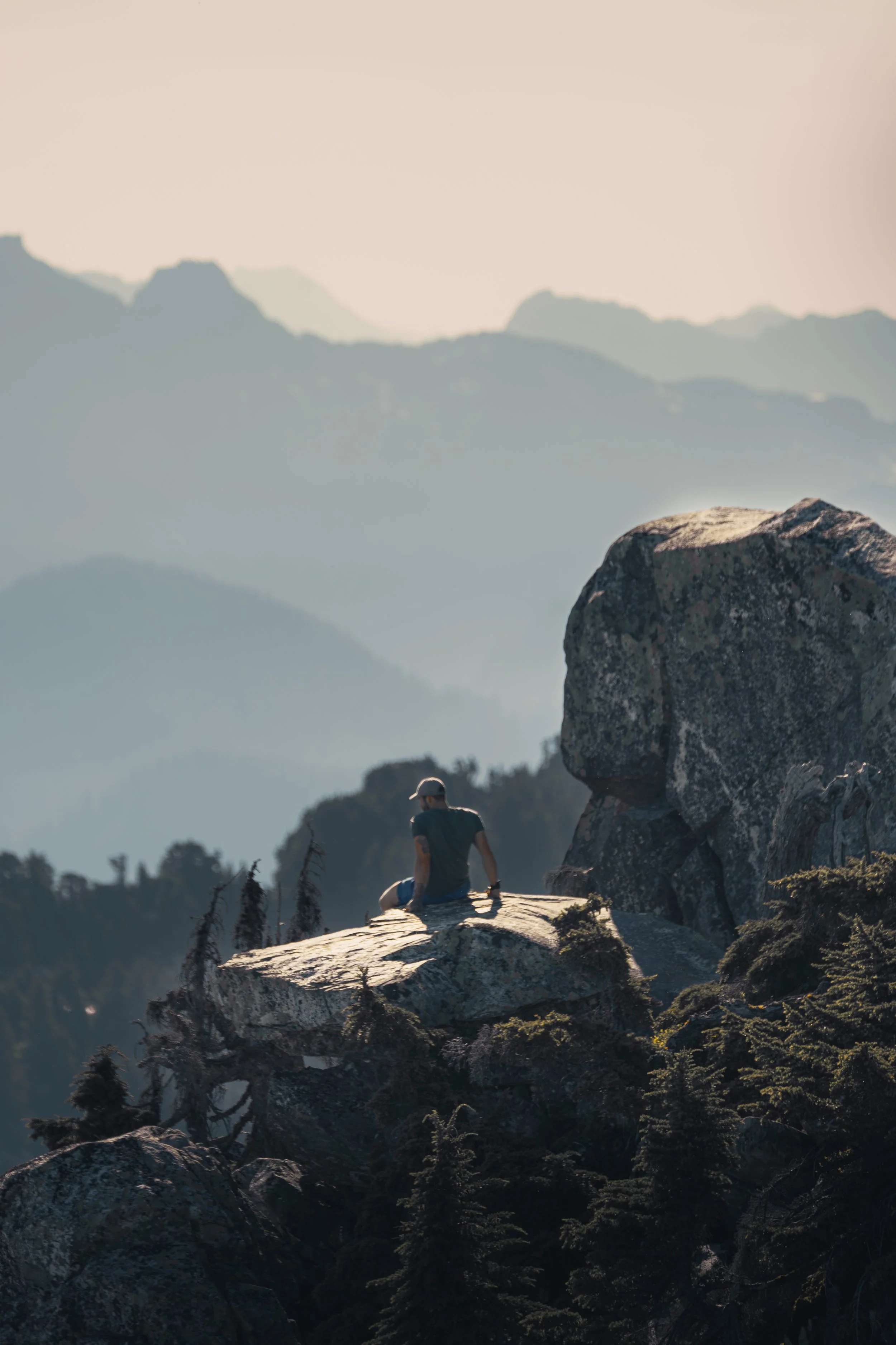 Hiker sitting on a rock ledge taking in the hazy mountain views at Mount Pilchuck.
Resting on the edge of the world. A hiker sits on a massive granite slab near the Mount Pilchuck summit, soaking in the quiet evening atmosphere of the Cascades.