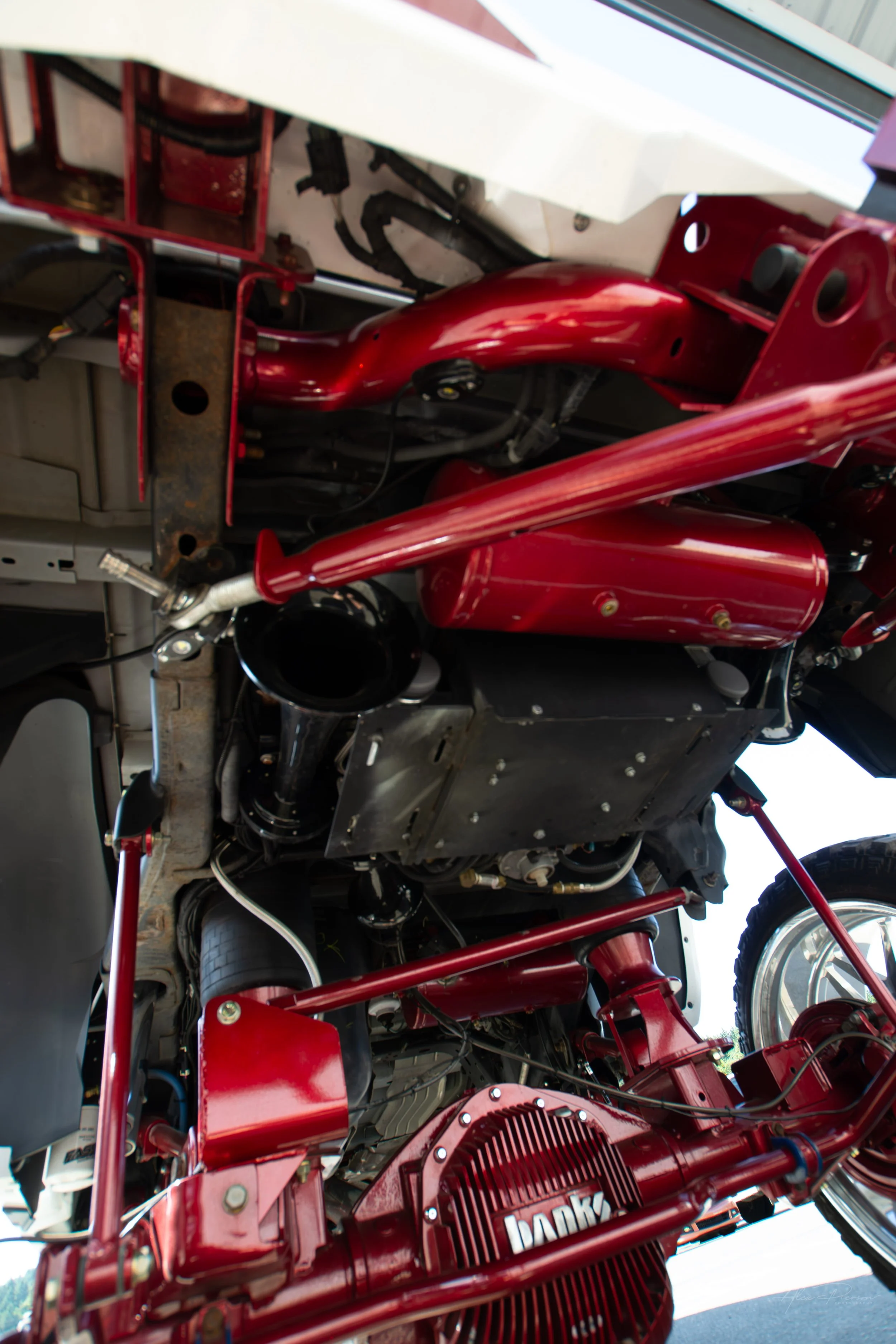 Upward-facing undercarriage view of a lifted Ram 2500 showcasing custom red air suspension tanks, heavy-duty train horns, and a Banks Power rear differential cover.

Custom train horns, truck air tanks, Ram 2500 undercarriage, lifted truck accessorie