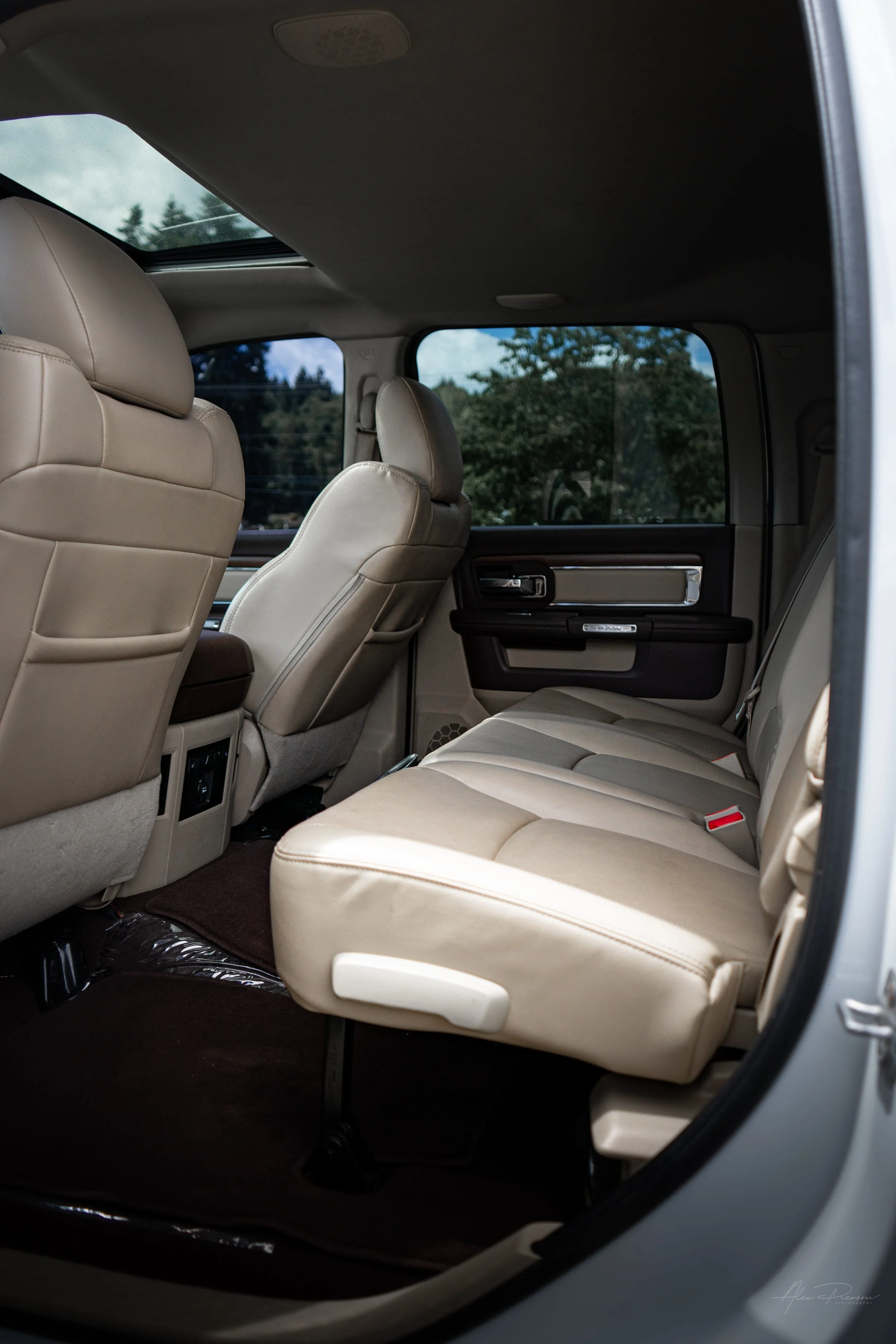 Spacious rear cab interior view of a Ram 2500 Laramie show truck, showcasing premium tan leather seating, fold-flat floor storage, and an open sunroof.
Ram 2500 rear seats, truck crew cab interior, tan leather back seat, Dodge Ram sunroof.
rear passe