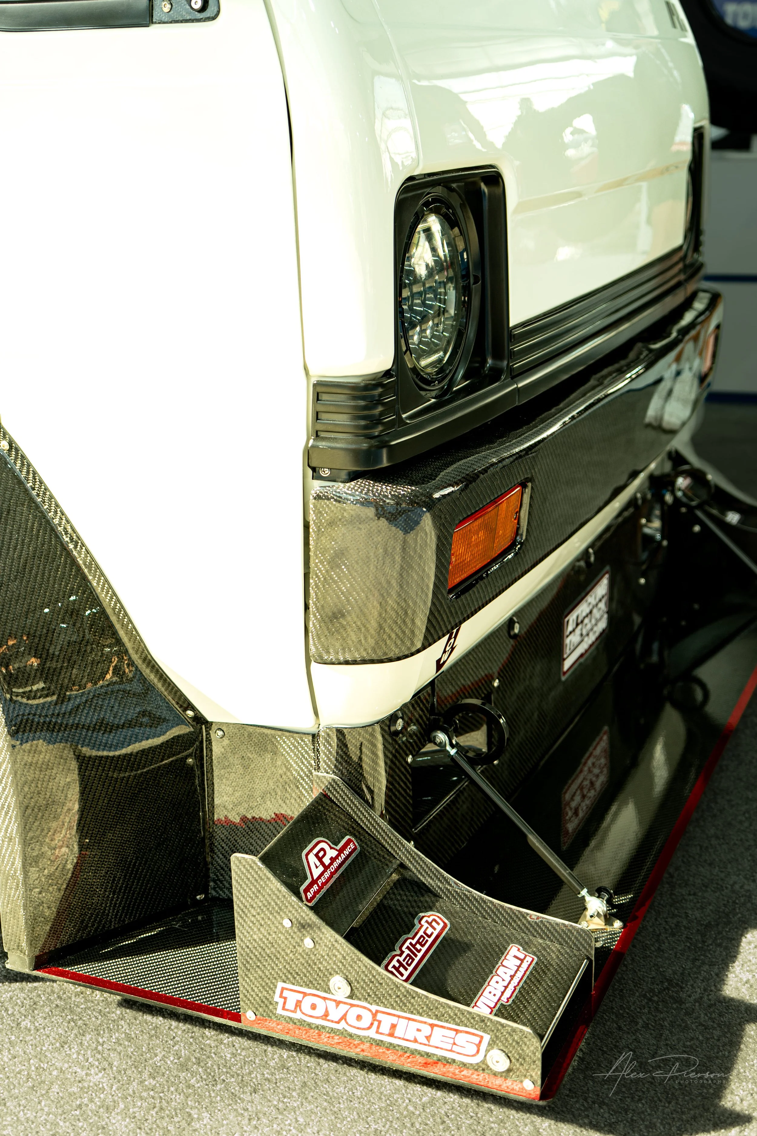 Close-up of the carbon fiber front splitter, LED headlights, and custom front bumper on a racing Kei truck at the SEMA Show.
Up-close look at the custom carbon fiber front splitter and modern LED headlights on a heavily modified Time Attack Kei truck