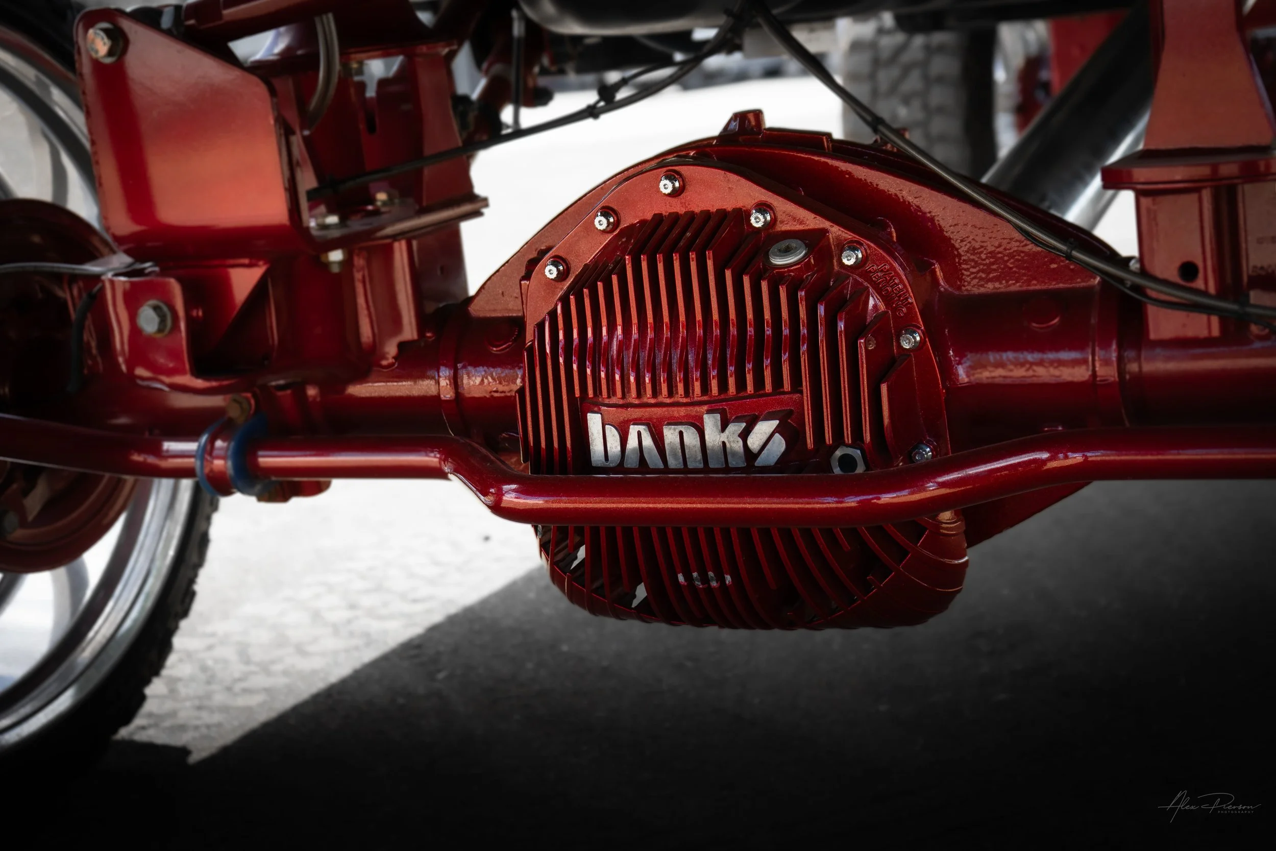 Heavy-duty Banks Power rear differential cover mounted on a custom candy red powder-coated axle with Kelderman air suspension components.
Banks differential cover, red truck axle, Ram 2500 diff cover, aftermarket differential.
Banks Power Ram 2500 re