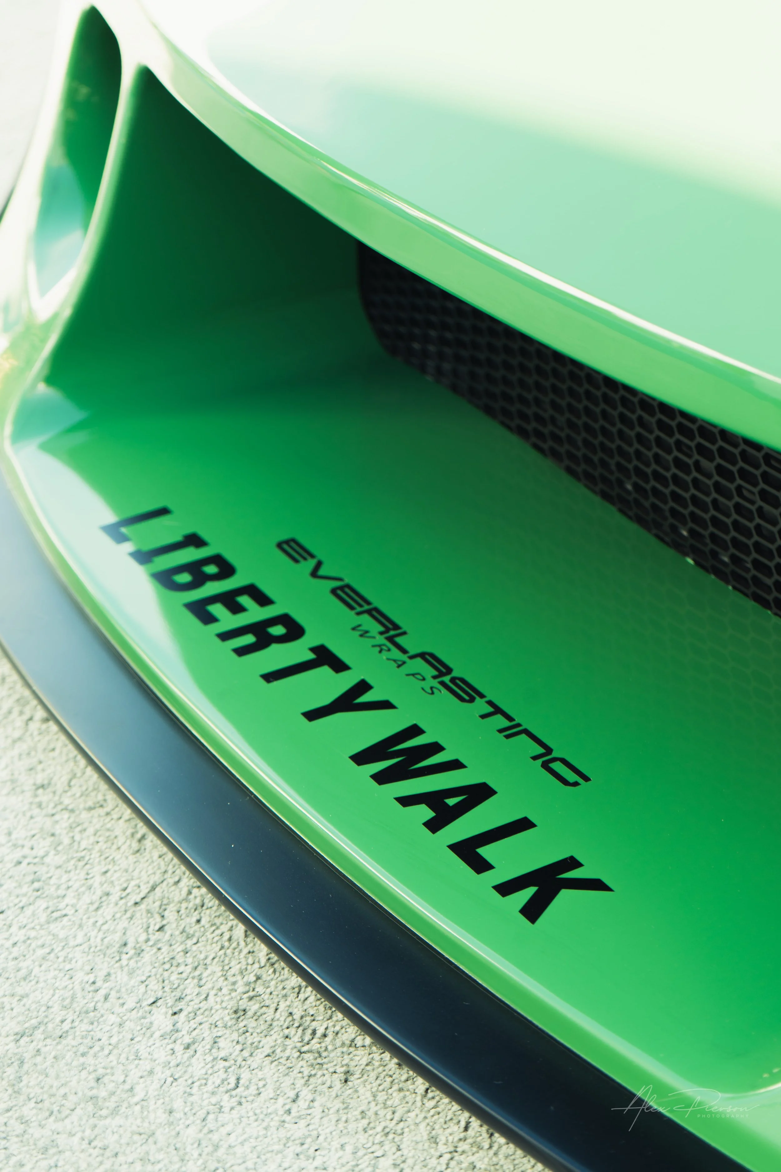 Close up of the front bumper and grille on a green Mazda RX-7 featuring Liberty Walk and Everlasting Wraps decals.
Up close with the details. The aggressive front bumper and mesh intake of a vibrant green Liberty Walk Mazda, wrapped to perfection for