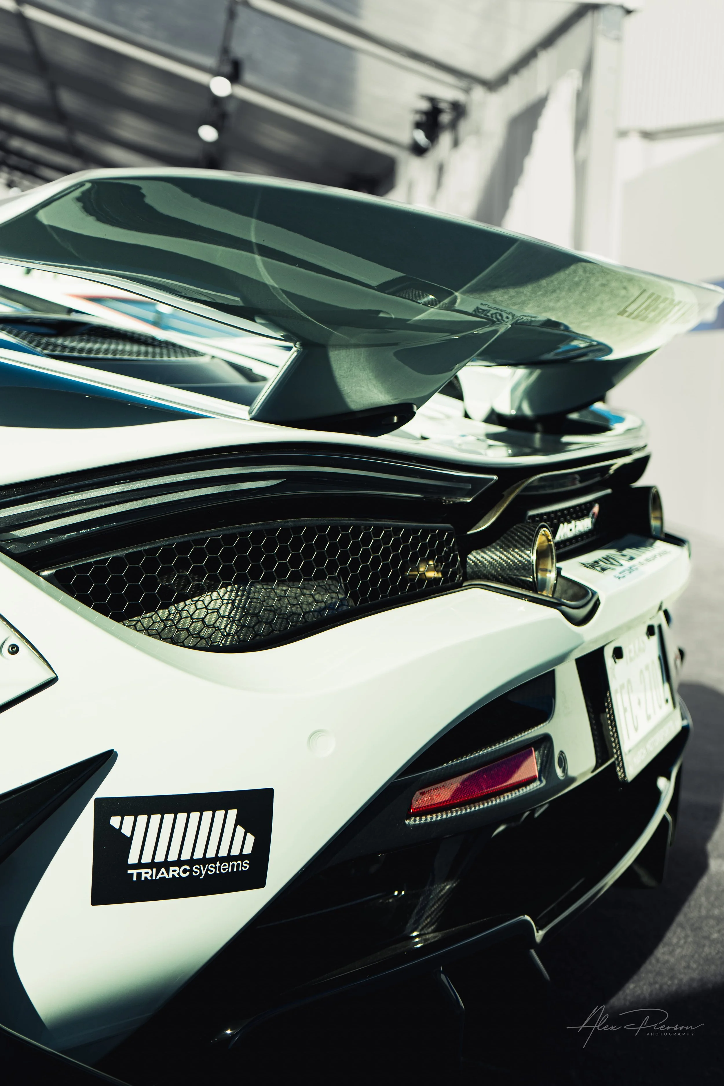 Rear detail of a grey McLaren 720S showing the active rear wing and carbon fiber exhaust surrounds.
Supercar details. A close-up of the McLaren's sculpted rear end, featuring carbon fiber exhaust shrouds, honeycomb venting, and an aggressive active r