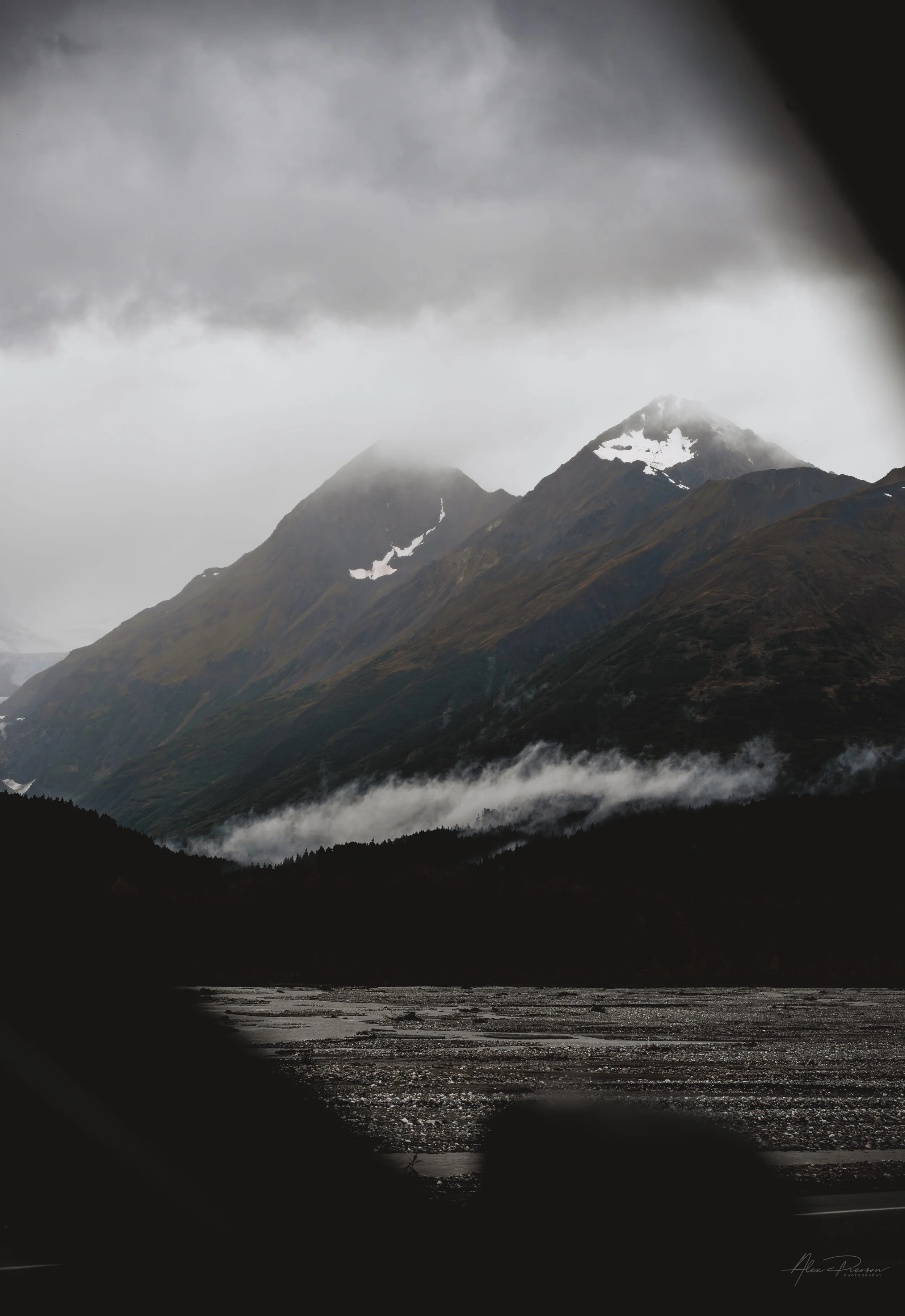 moody-alaska-mountain-peaks-low-clouds-river-bed.jpg
