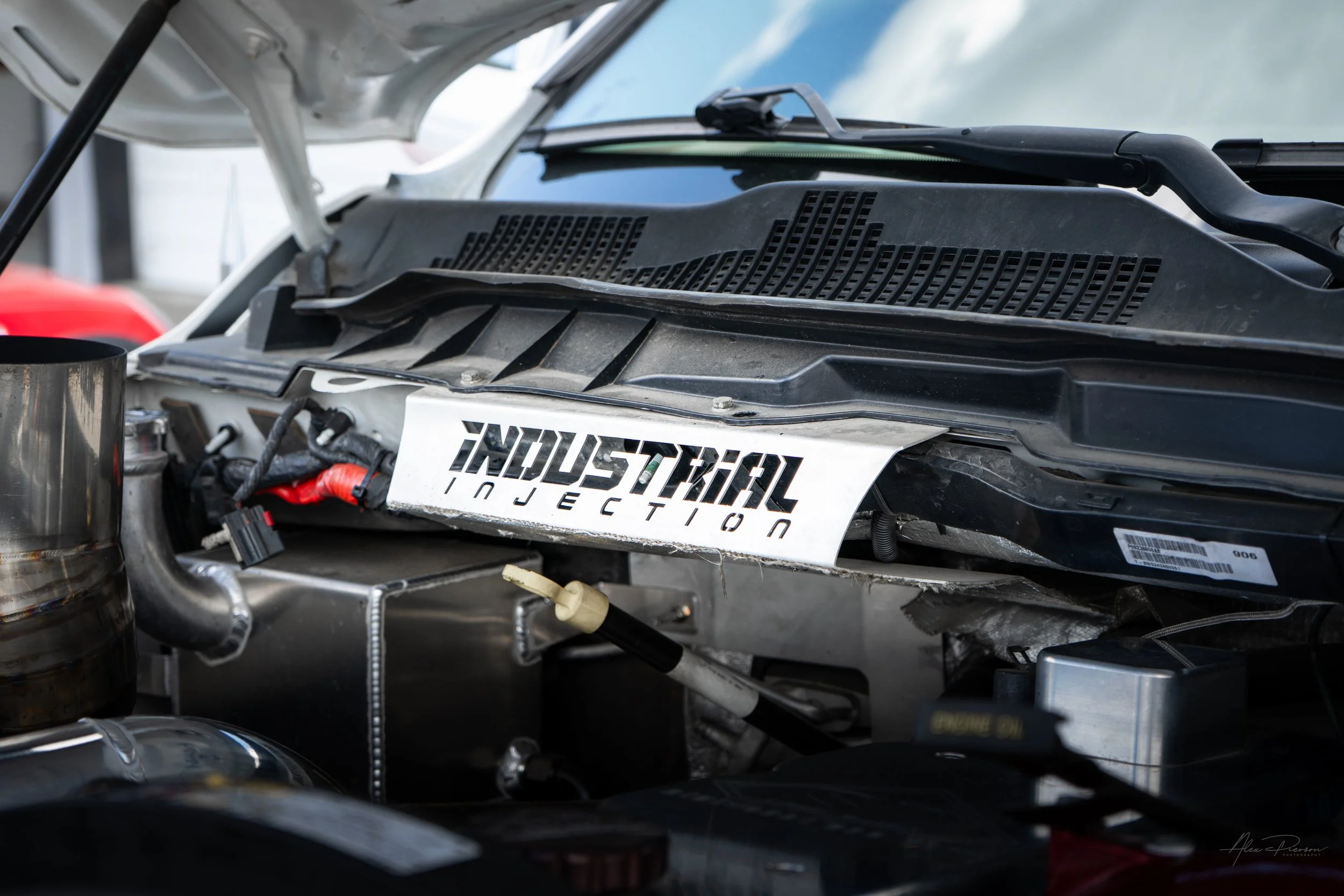 Detail shot of a custom Industrial Injection trim plate mounted above the firewall in the engine bay of a high-performance lifted diesel Ram 2500.
 Industrial Injection, Cummins engine trim, diesel firewall cover, Ram 2500 upgrades.
custom Industrial