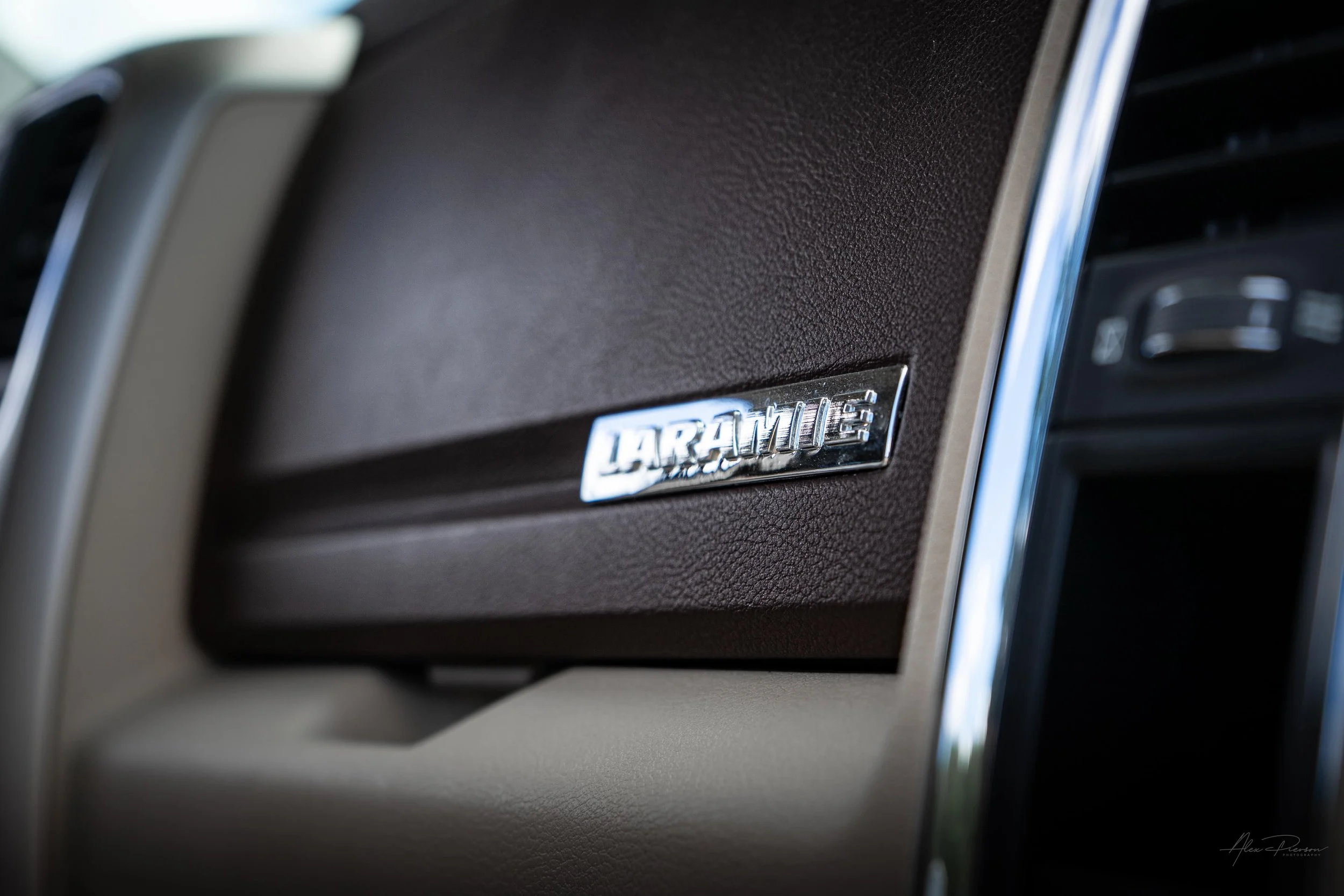 Close-up detail of the premium Laramie edition chrome badge mounted on the stitched leather-wrapped dashboard inside a custom Dodge Ram 2500.
Ram Laramie badge, leather truck dashboard, Ram 2500 interior, luxury truck dash.
chrome Laramie trim badge 