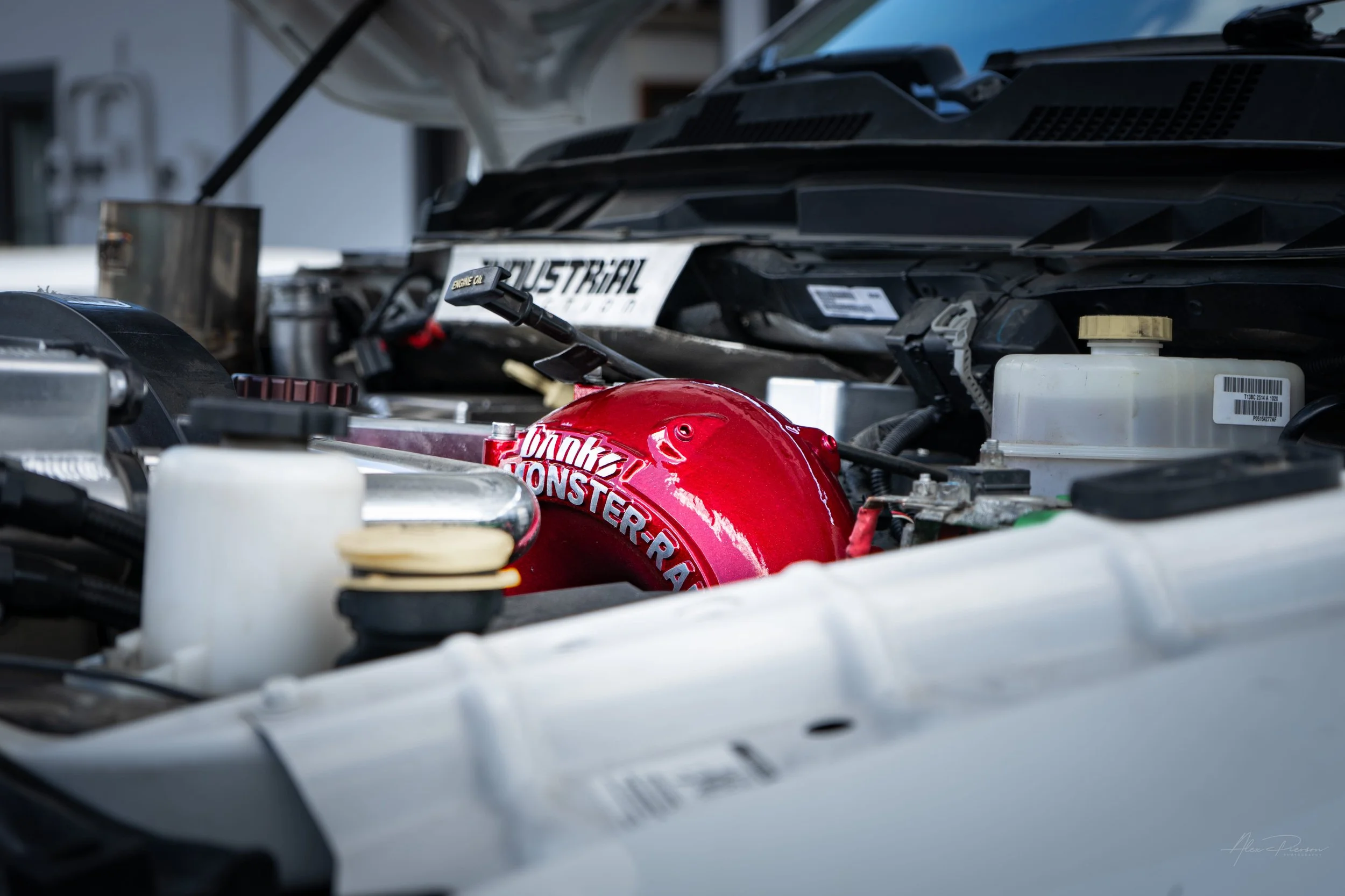 Upgraded Ram 2500 Cummins diesel engine bay highlighting a red Banks Monster-Ram intake and an Industrial Injection custom firewall cover plate.
Industrial Injection plate, Banks intake Cummins, tuned Cummins, custom diesel engine bay.
 Industrial In