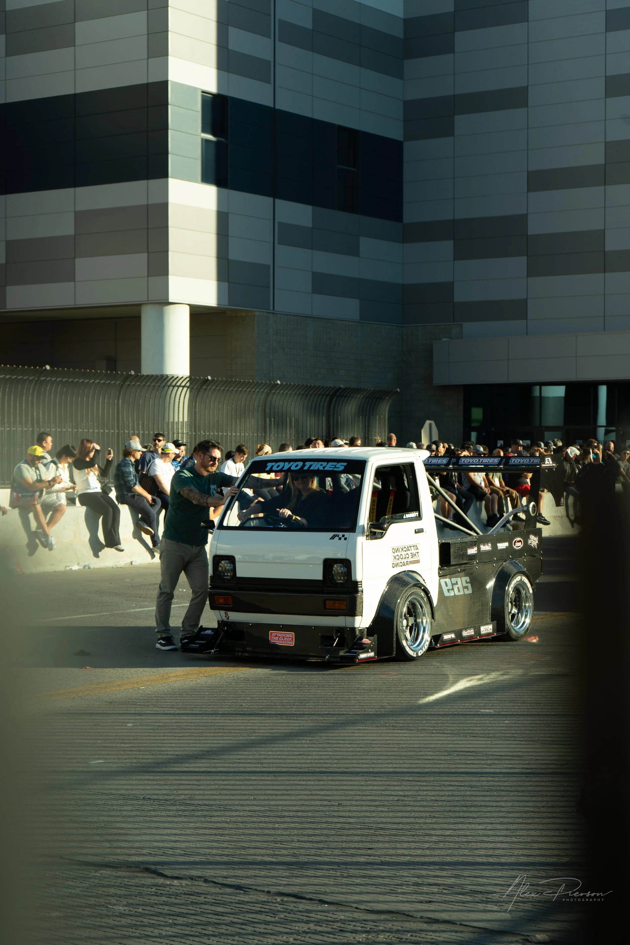 A heavily modified widebody Kei truck with a massive rear wing driving out of the Las Vegas Convention Center during the SEMA Rollout.

Golden hour automotive photography of a widebody Time Attack Kei truck leaving the Las Vegas Convention Center dur