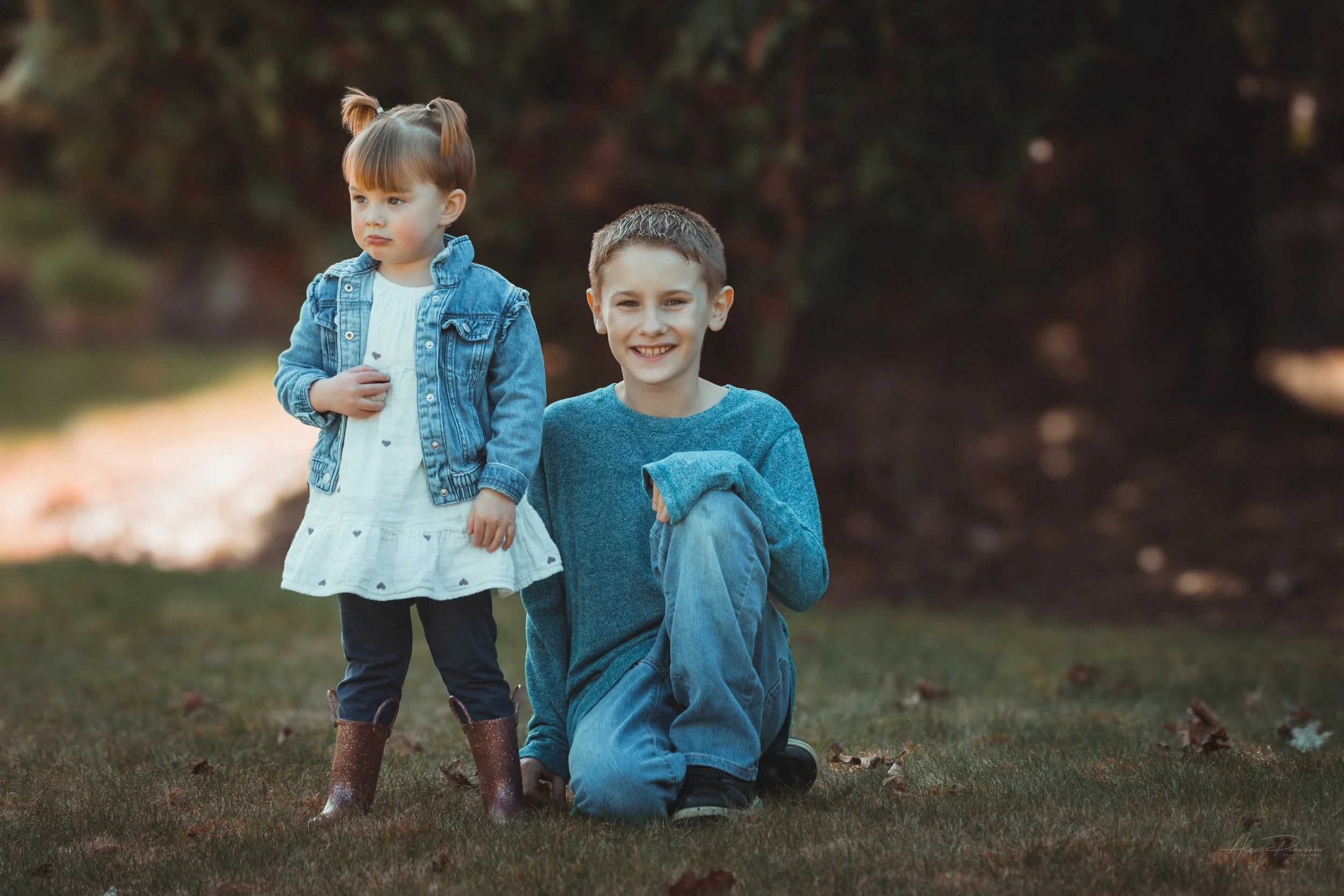 Little girl in a white dress standing with her cousin, looking directly at the camera during an outdoor portrait shoot in Tumwater, WA– Pacific Northwest lifestyle family and children's photography.