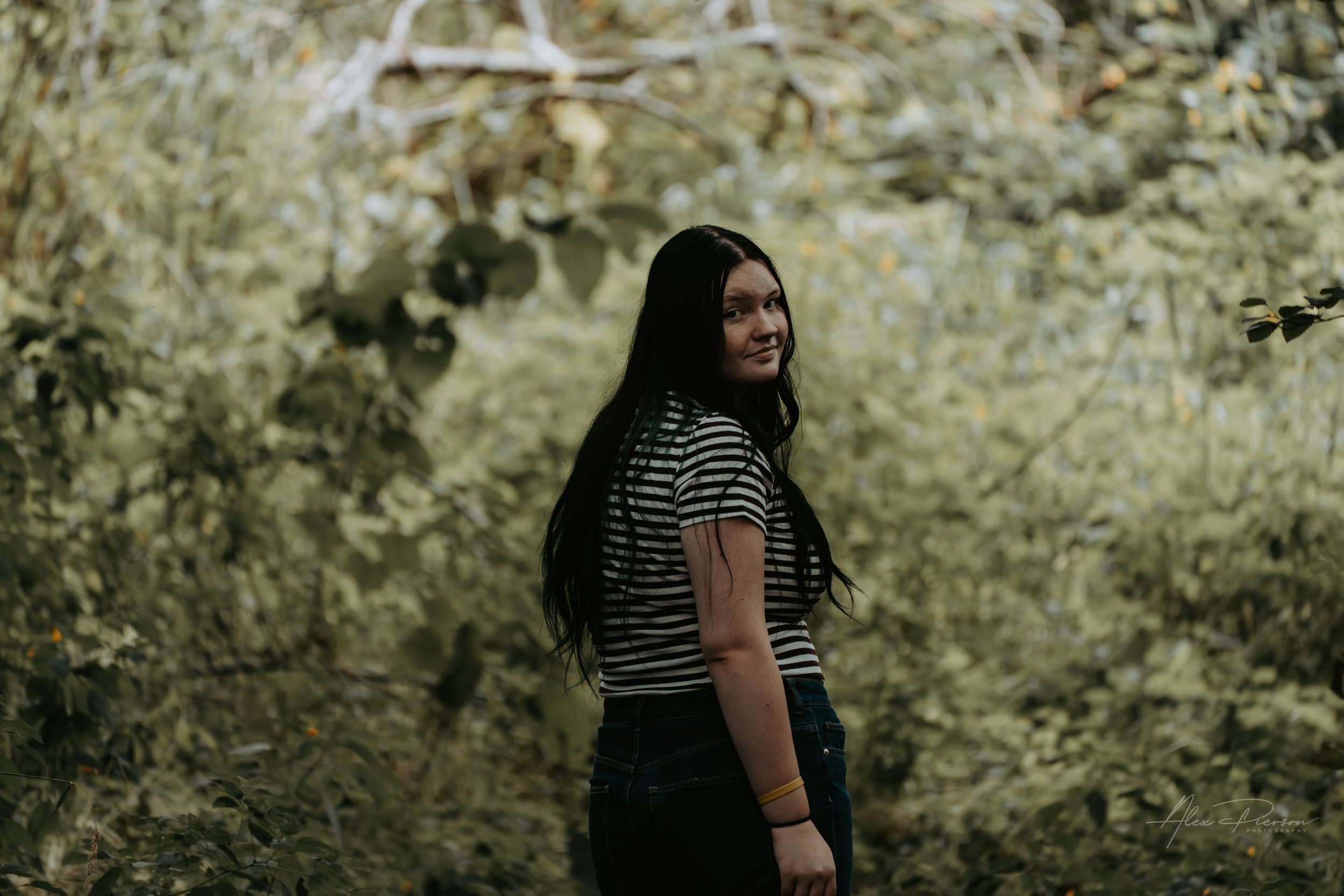 An up close portrait of a young lady wearing a black and white striped shirt while she is turning to look at the camera during a family photoshoot in Montesano, WA- – Pacific Northwest lifestyle family and children's photography.