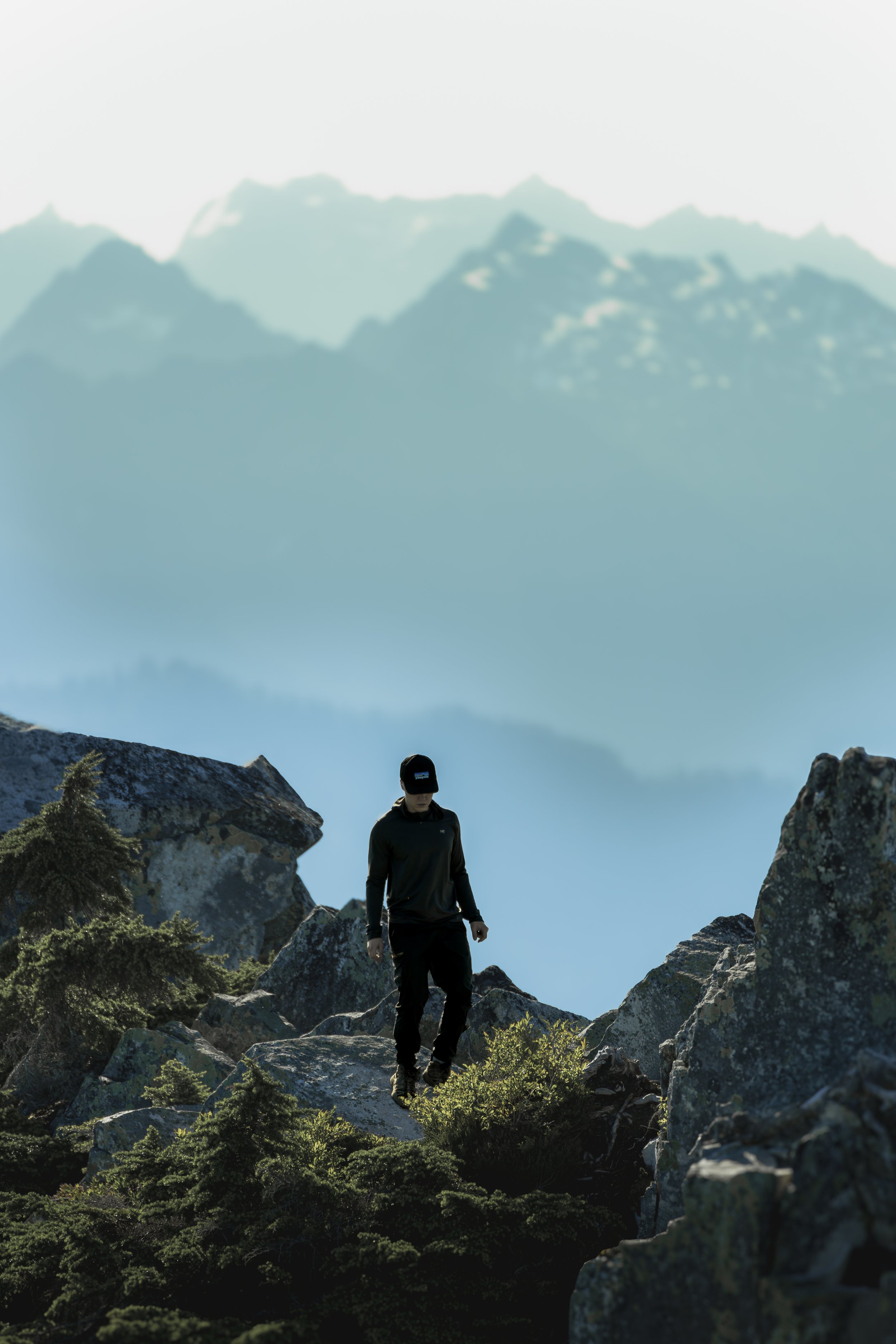 A hiker carefully navigates a rocky alpine trail with massive hazy blue mountains in the background.
Navigating the rugged granite terrain near the Mount Pilchuck Fire Lookout, with the massive, hazy peaks of the North Cascades towering in the backgr