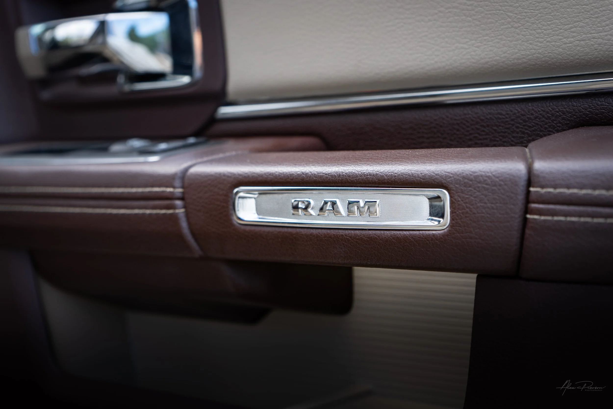Detailed interior view showing the chrome RAM emblem on the premium stitched brown leather door panel of a lifted Ram 2500 Laramie.
Ram 2500 interior, leather door panel, Ram truck emblem, Laramie interior.
premium brown leather door panel with chrom