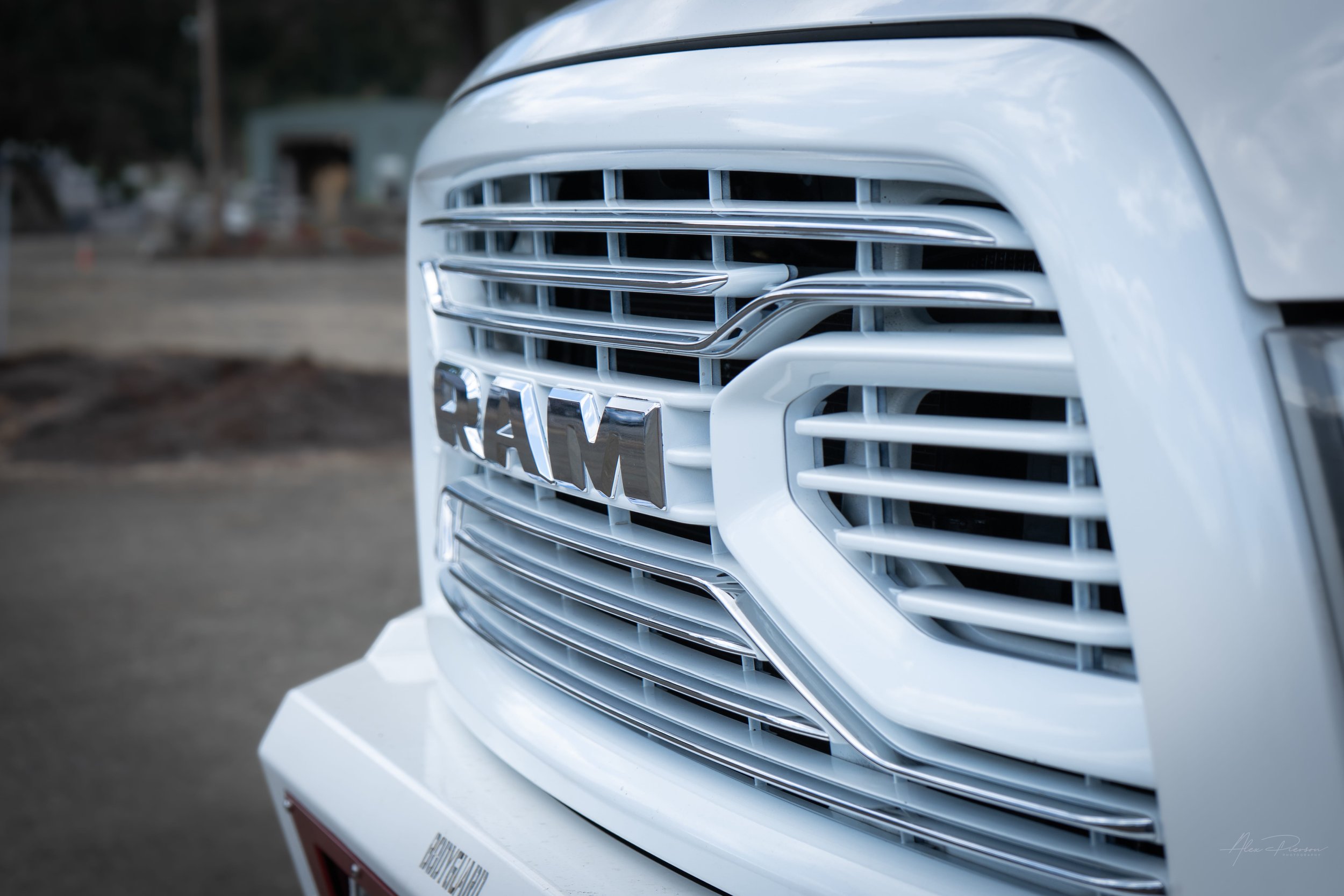 Close-up detail of a custom color-matched white and chrome front grille on a modified Ram 2500 Heavy Duty show truck.
Ram 2500 custom grille, white truck grille, chrome Ram grille, custom truck front end.
 color-matched white and chrome front grille 