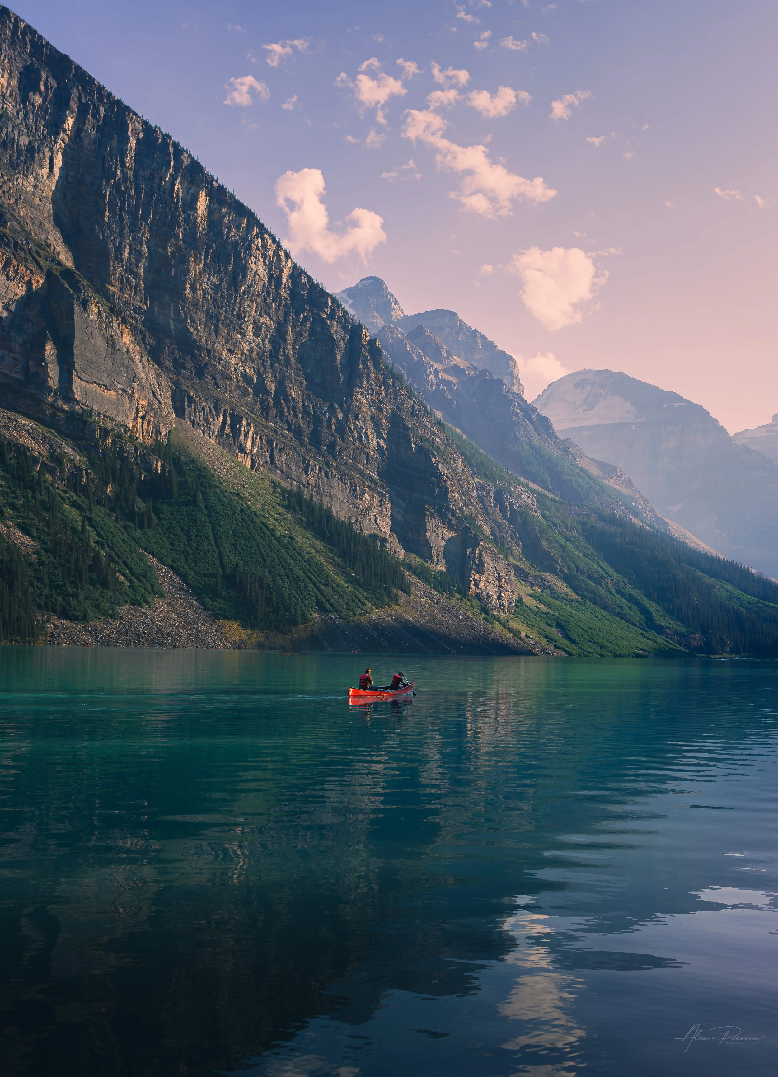 A bright red canoe floating on the turquoise water of Lake Louise beneath massive mountain cliffs.
A quintessential Canadian Rockies experience. A bright red canoe paddles across the impossibly blue waters of Lake Louise, dwarfed by the sheer, dramat