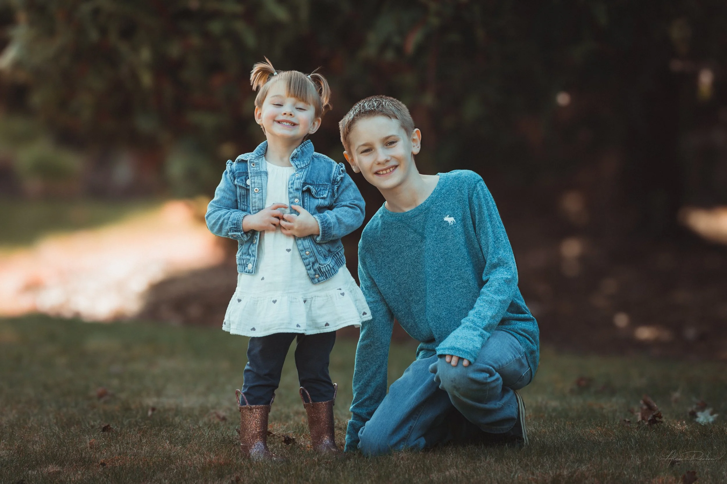 Little girl in a white dress standing with her cousin, looking directly at the camera during an outdoor portrait shoot in Tumwater, WA– Pacific Northwest lifestyle family and children's photography.