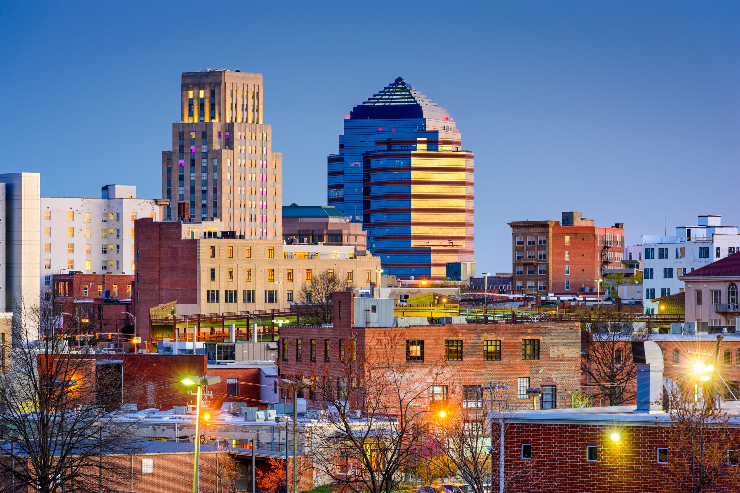 Downtown Durham, North Carolina skyline with modern and historic buildings at dusk, featuring a prominent skyscraper.