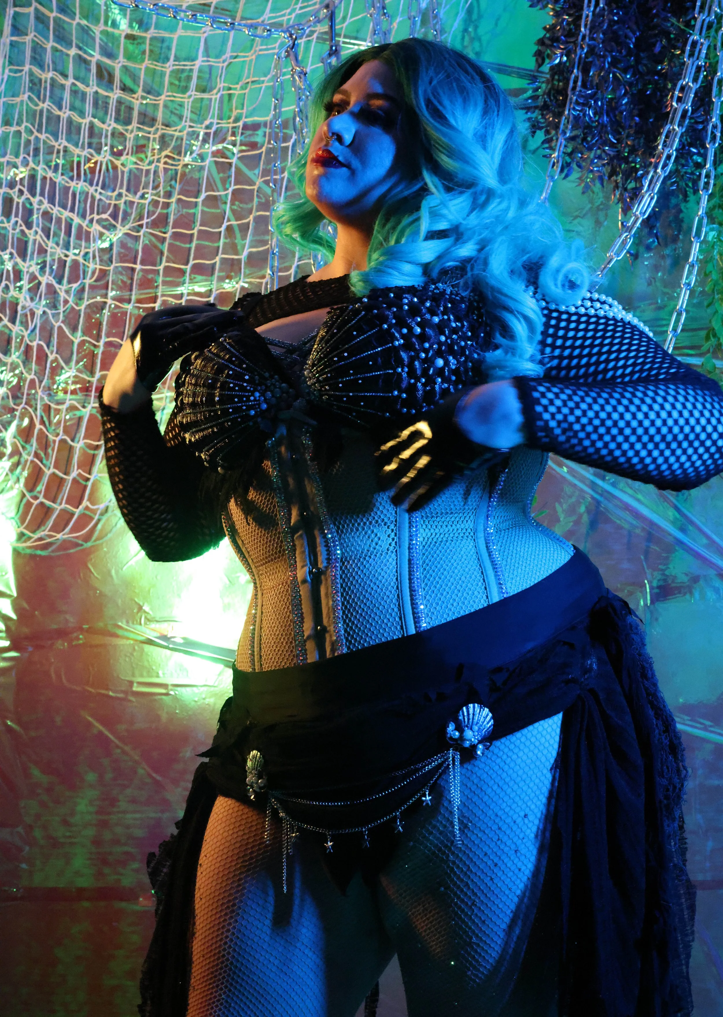 MerDomina strikes a pensive, artful pose in turquoise hair and a sparkly black mermaid burlesque-inspired costume