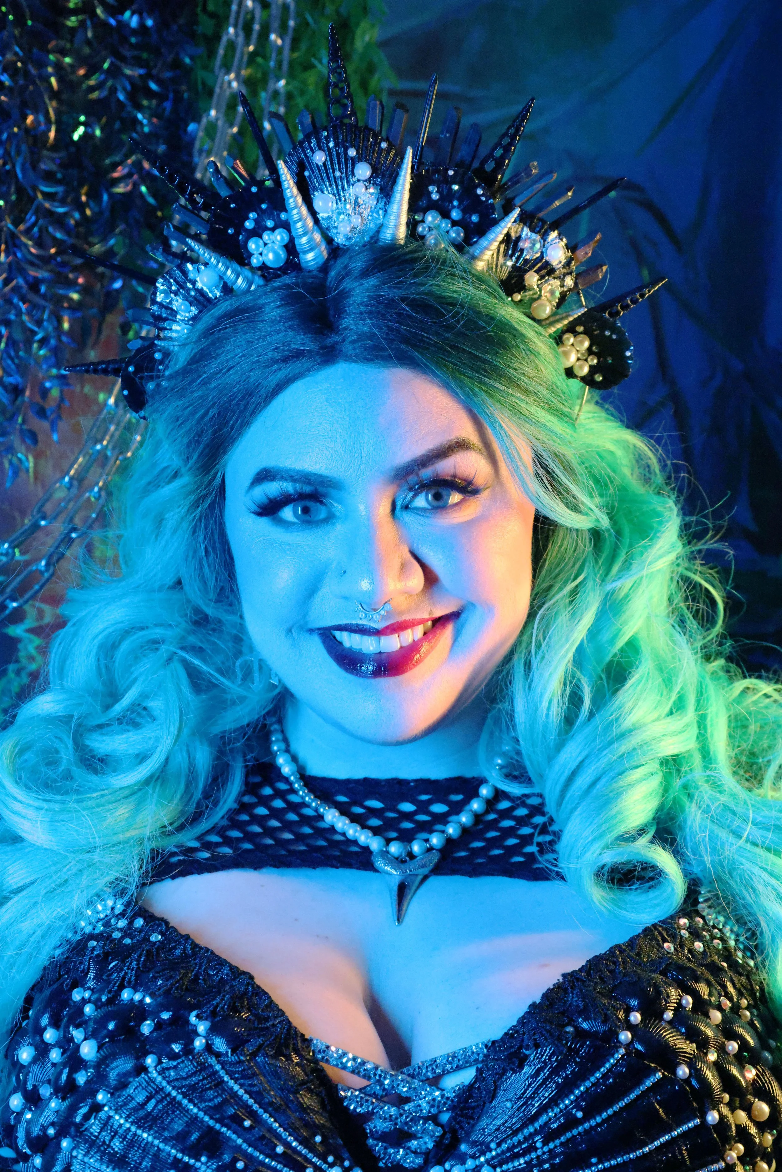 MerDomina smiles in turquoise hair, red lips, a handmade shell crown, and a handmade shell bra