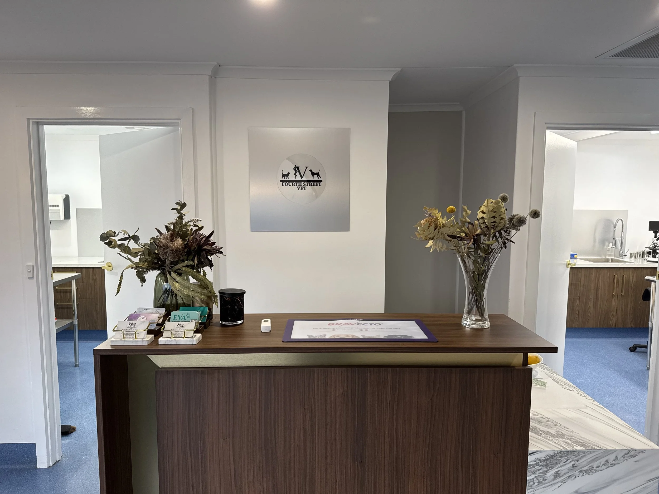 Reception desk with a bouquet of flowers, promotional pamphlets, and a sign for Fourth Street Vet, in a clean, modern office area with white walls.