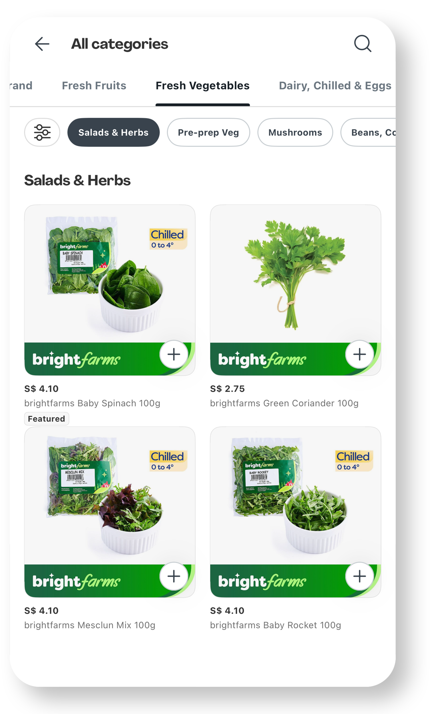 Screenshot of a grocery app showing different fresh vegetables under the 'Salads & Herbs' section. The vegetables include baby spinach, green coriander, mesclun mix, and baby rocket, each in plastic packaging and some labeled as 'Chilled' with a temperature range of 0 to 4 degrees Celsius. Prices are listed in S dollars.