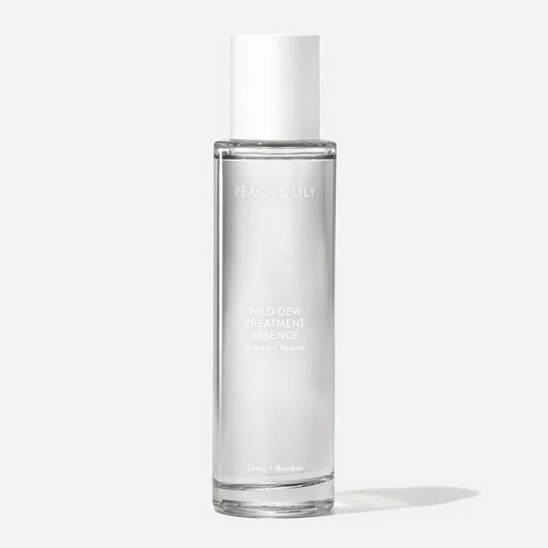 A clear cylindrical bottle with a white cap containing Peach & Lily Wild Dew Treatment Essence; the bottle has minimalistic white text on it.