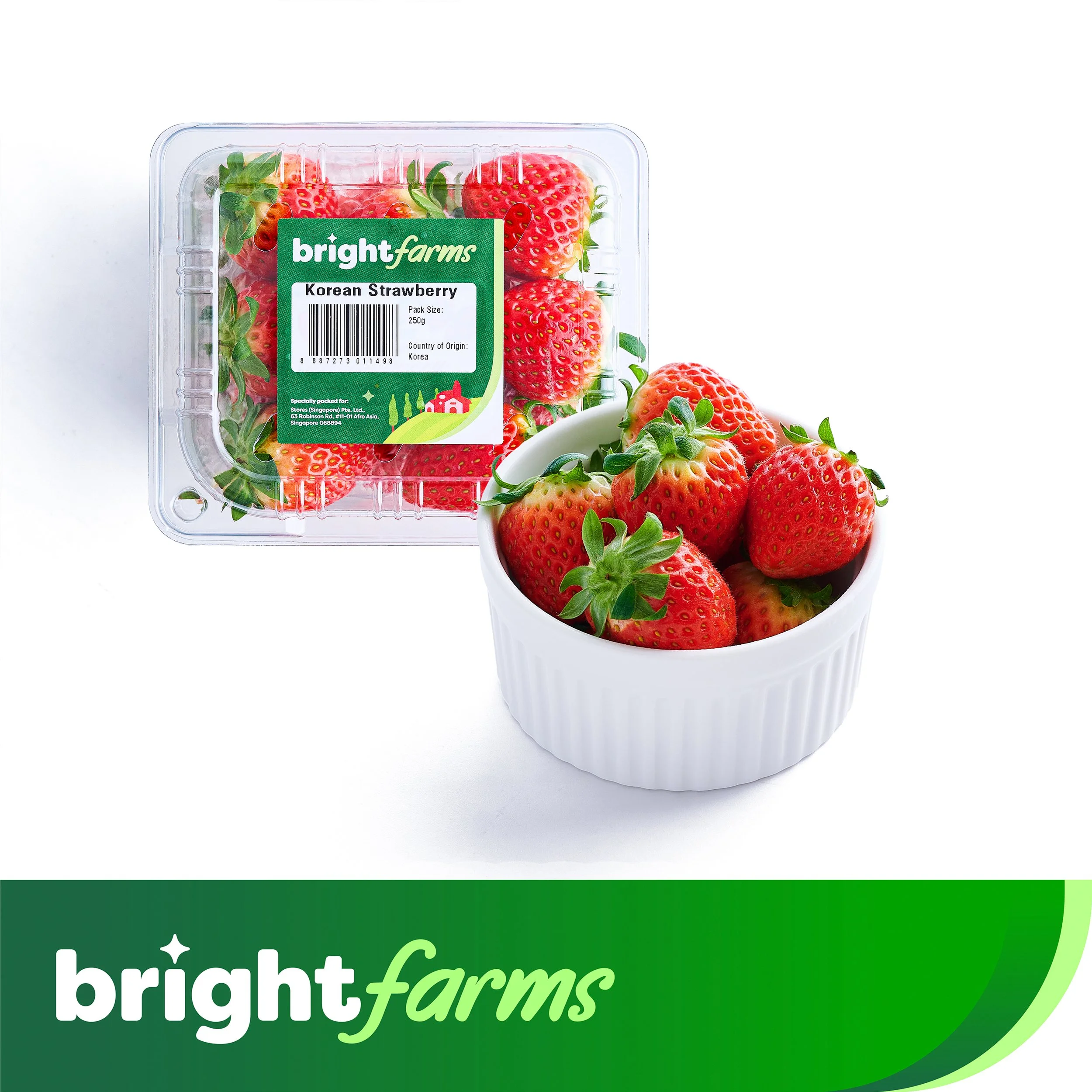 Fresh red strawberries in a white bowl and a plastic container of strawberries with a label reading 'bright farms' and 'Korean Strawberry'.
