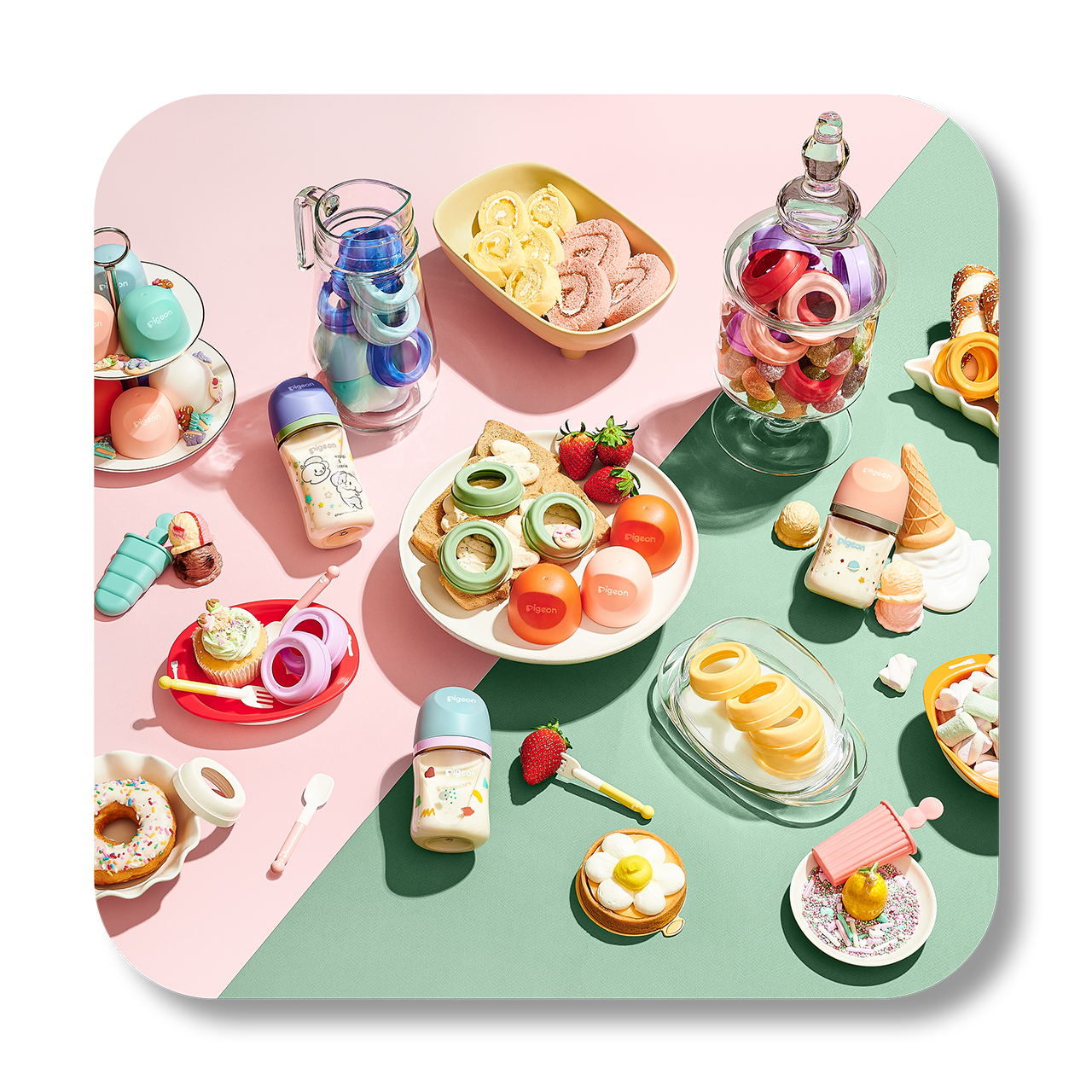 Array of colorful toy food and drink accessories including donuts, ice cream, strawberries, and various bottles and containers on a pink and green background.