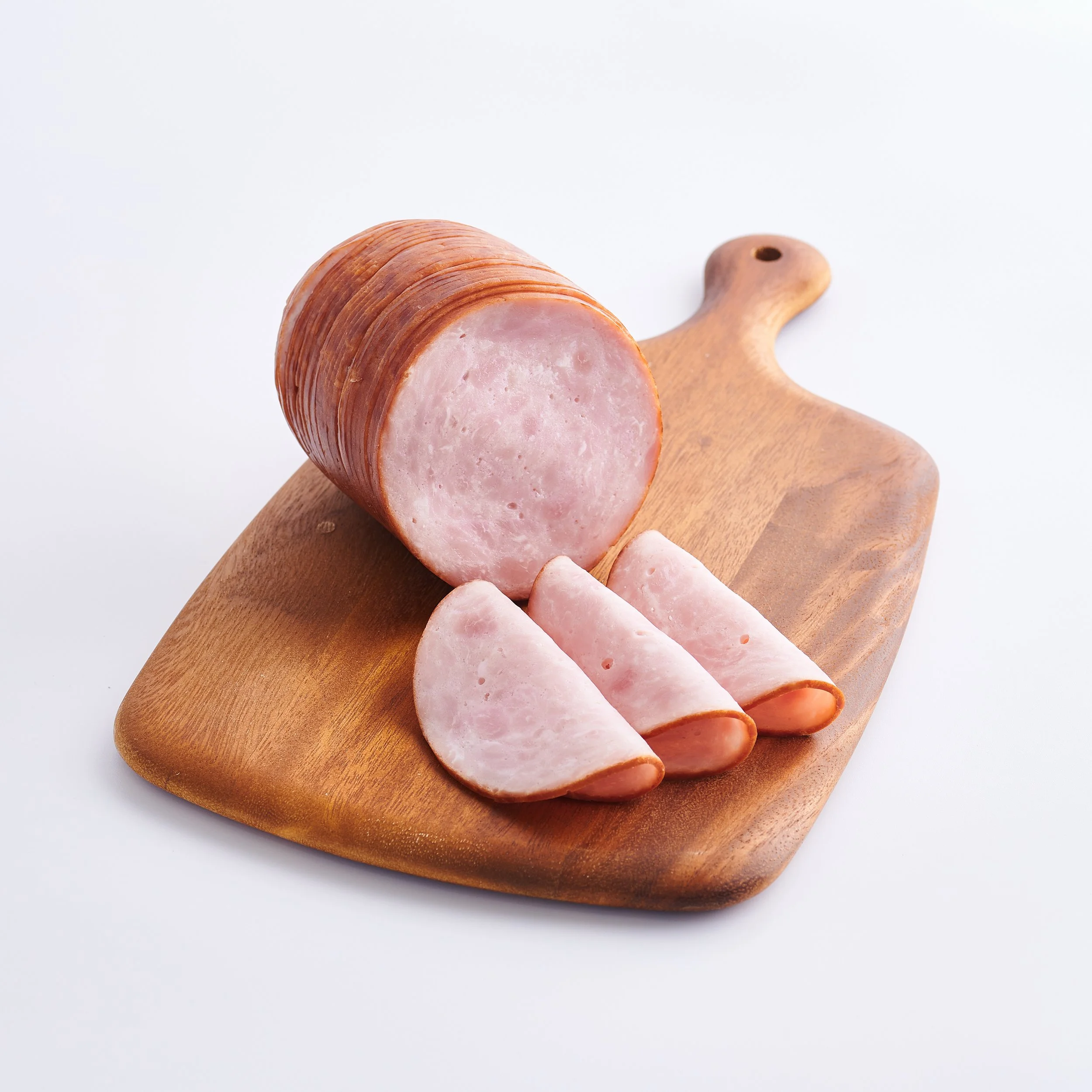 Sliced ham on a wooden cutting board against a white background
